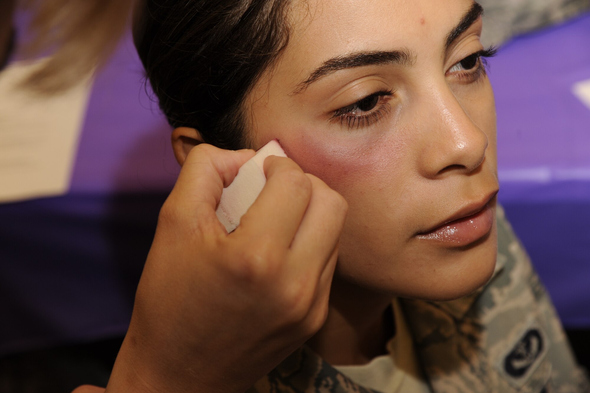 VANDENBERG AIR FORCE BASE, Calif. - Senior Airman Isabel Perri, a 30th Civil Engineer Squadron member, applies makeup to create a black eye during a Black Eye Campaign at the Balfour Beatty Community Center here Thursday, Oct. 6, 2011. The Black Eye Campaign helps to instruct the public on how to approach an individual who appears to be a victim of domestic violence. (U.S. Air Force photo/Senior Airman Lael Huss)
