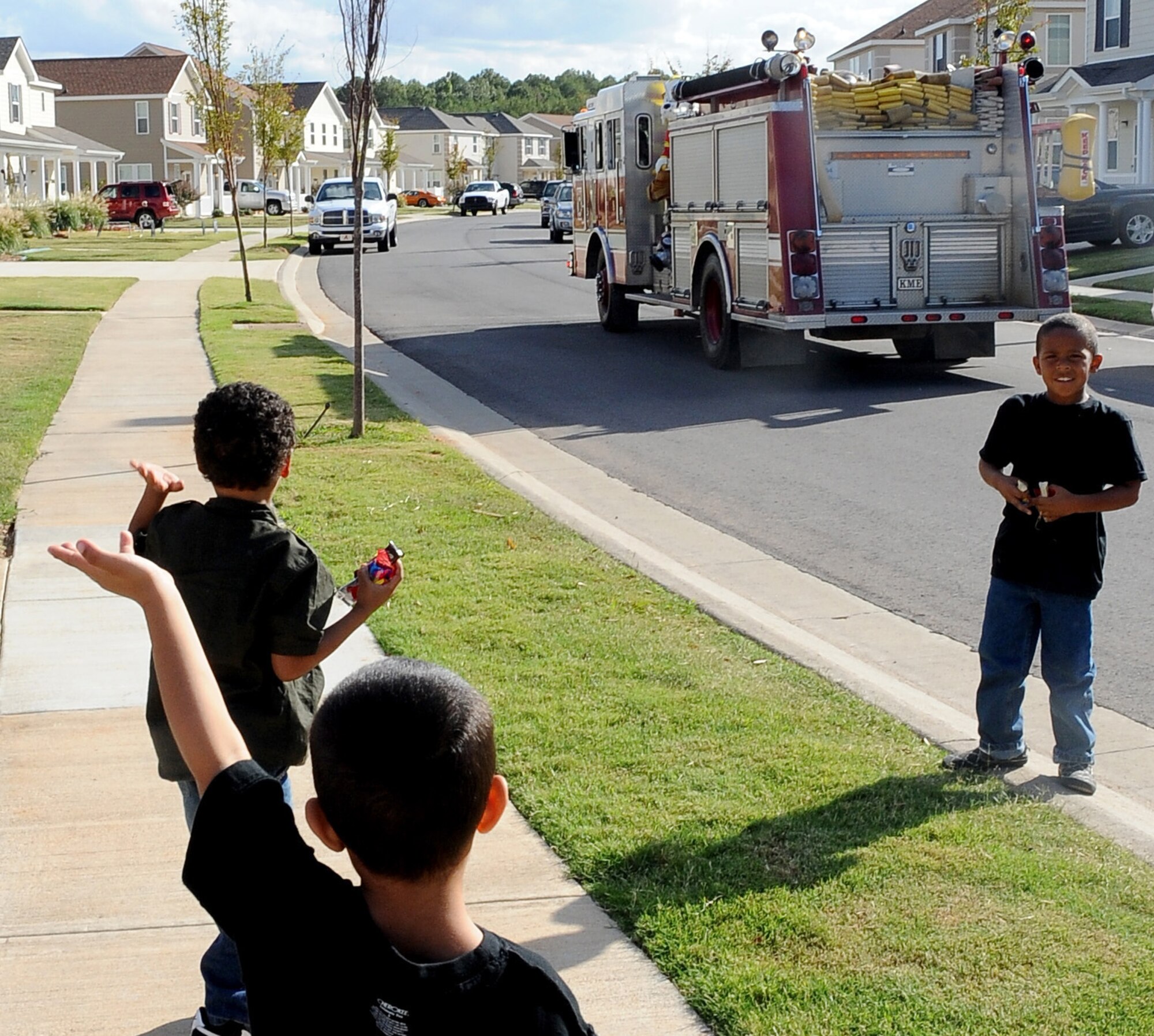 Children wave to a passing fire truck on Barksdale Air Force Base, La., Oct. 9. Sparky, the fire prevention mascot, along with several Airmen from the Barksdale Fire Department, rode through base housing to bring awareness to the beginning of Fire Prevention week. (U.S. Air Force photo/Senior Airman Amber Ashcraft)(RELEASED)