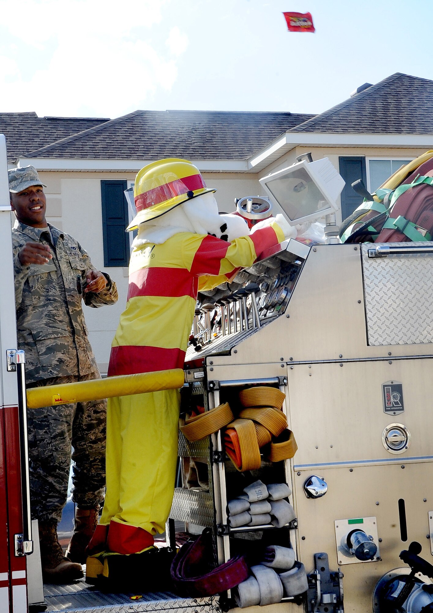 Airman 1st Class Reginald Bramlett, 2nd Civil Engineer Squadron firefighter, assists Sparky, the fire preventions mascot, in tossing candy to children in base housing on Barksdale Air Force Base, La., Oct. 9. Sparky rode along with one of Barksdale's fire trucks through base housing to bring awareness to the beginning of Fire Prevention week. (U.S. Air Force photo/Senior Airman Amber Ashcraft)(RELEASED)