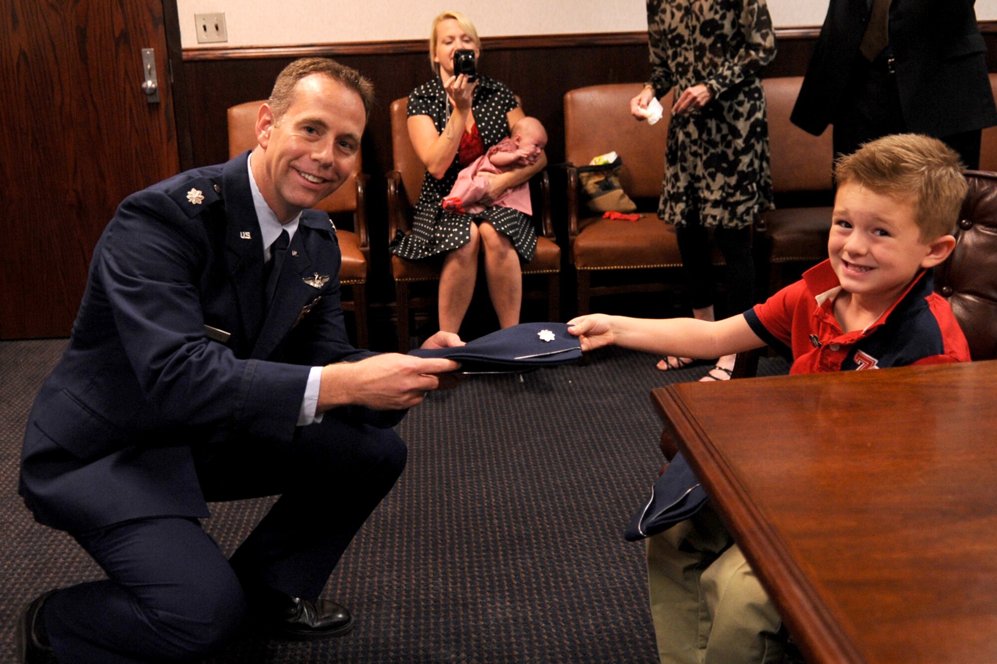 Dane Anderson presents his dad, U.S. Air Force Lt. Col. Chris Anderson, with his new Lt. Col. hat during a pinning-on ceremony at Barksdale Air Force Base, La., Oct. 7, 2011. Anderson is a B-52 radar navigator and Chief of Weapons Training for the 93rd Bomb Squadron, 307th Bomb Wing. (U.S. Air Force photo by Master Sgt. Greg Steele/Released)