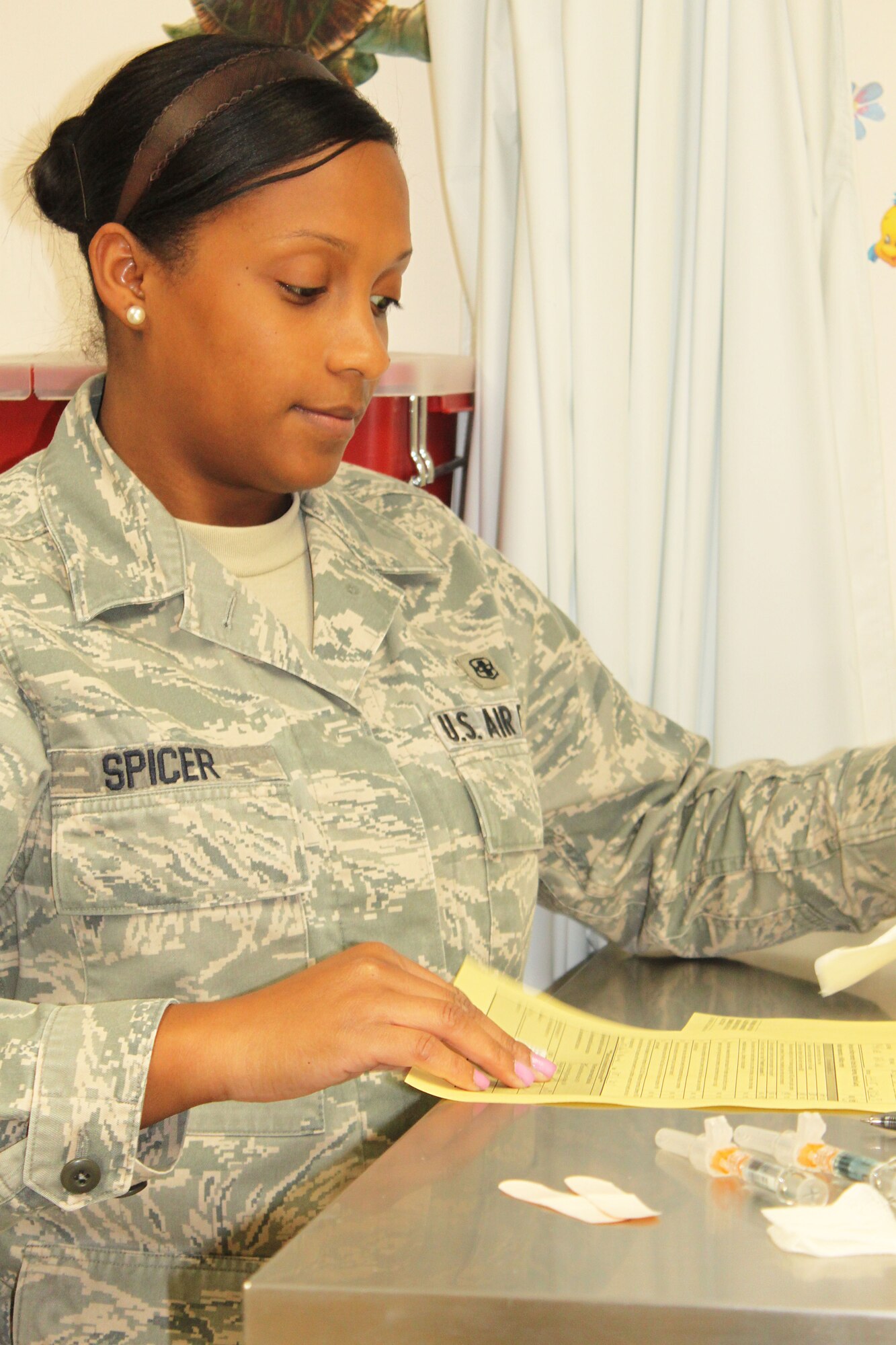 Senior Airman Melissa Spicer, allergy immunization
technician, 95th Medical Squadron, prepares a patient's shot record before administering the flu vaccine. (U.S. Air Force photo by Meredith Mingledorff) 