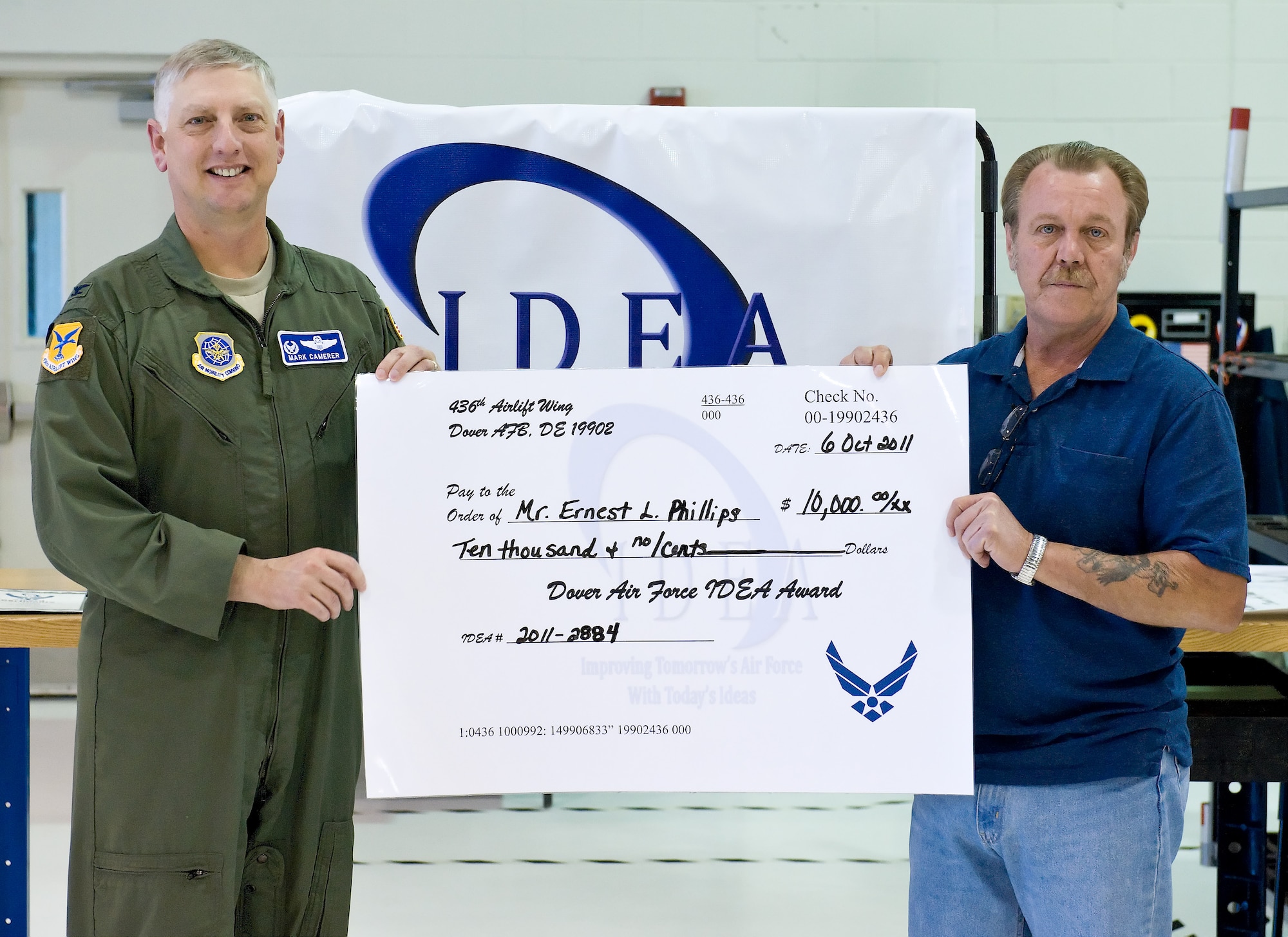 Col. Mark Camerer, commander of the 436th Airlift Wing, presents Larry Phillips, jet-engine-module-repair shop supervisor with the 436th Maintenance Squadron, with a $10,000 check for his submission to the Air Force’s Innovative Development through Employee Awareness program Oct. 6, 2011, at Dover Air Force Base, Del. Phillips has won more than $40,000 for his IDEA submissions, which have improved the repair process for the TF-39 engine.  (U.S. Air Force photo by Roland Balik)