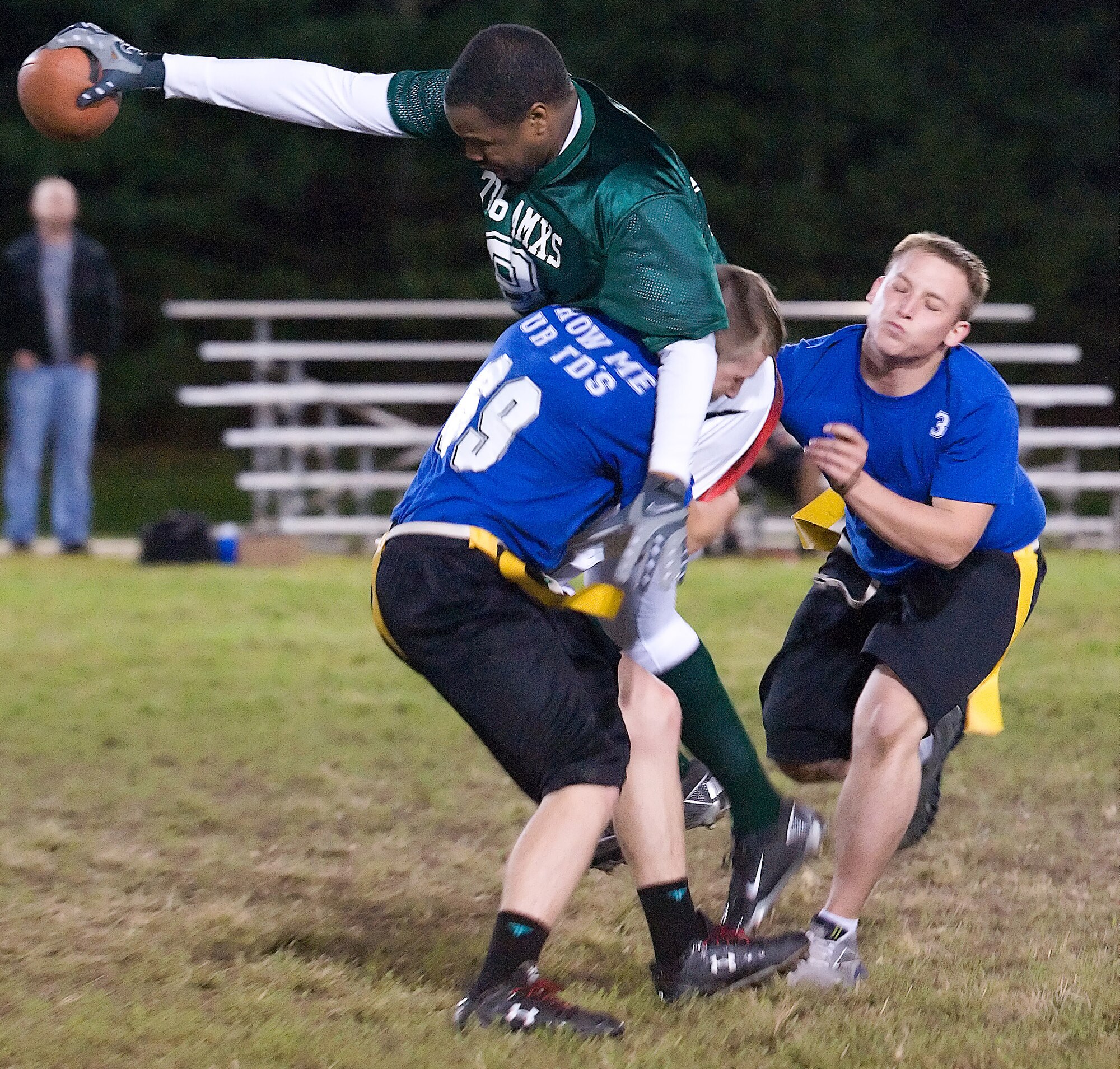 Andre Leonard (green), is wrapped up by David Atwood as Devin Krozek rushes in to help Oct. 6, 2011, at Dover Air Force Base, Del. The 736th Aircraft Maintenance Squadron defeated the 436th Communications Squadron 42-21. (U.S. Air Force photo by Airman 1st Class Samuel Taylor)