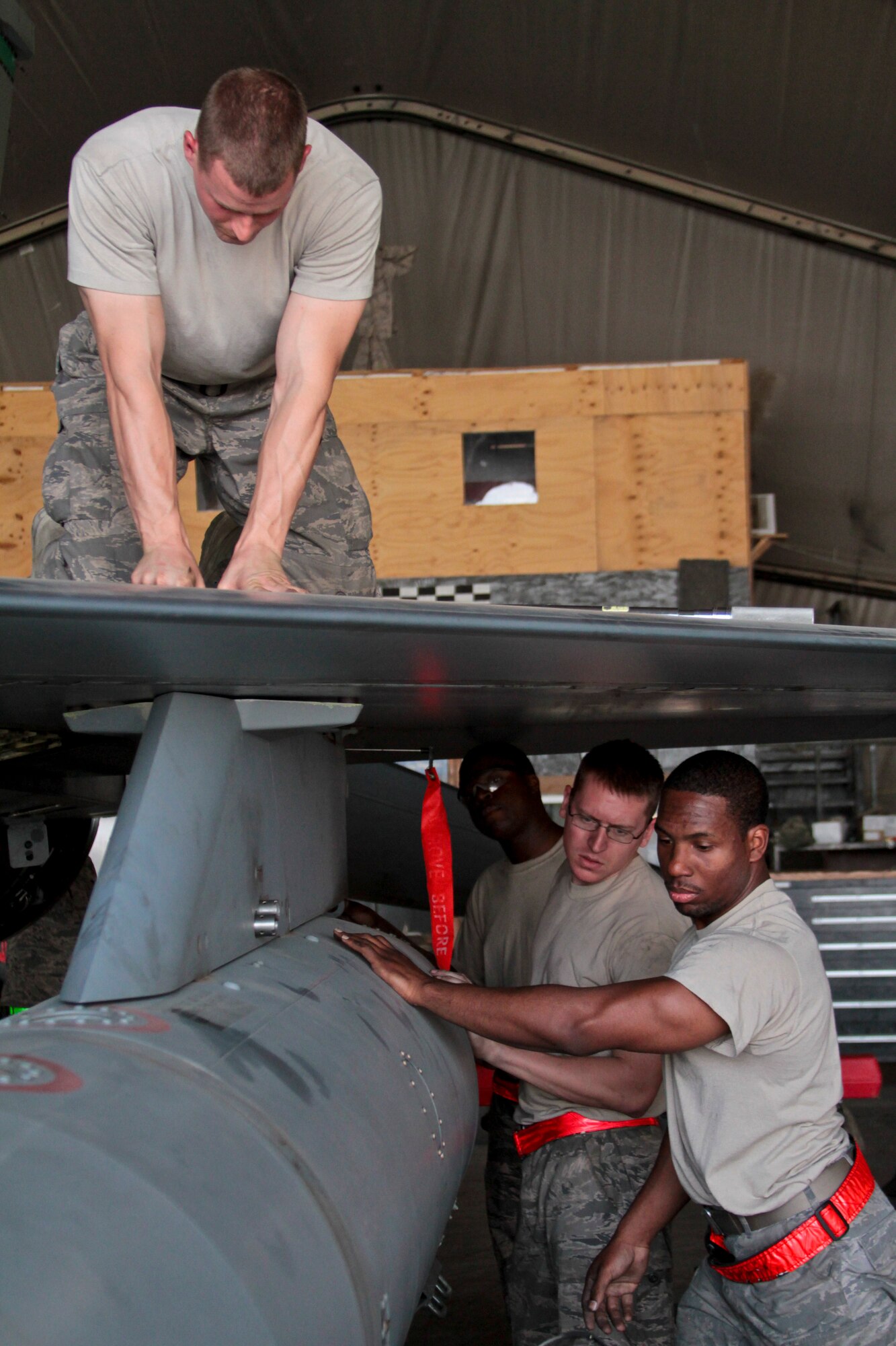Airman 1st Class Adam Sexton, a 455th Expeditionary Aircraft Maintenance Squadron crew chief, tightens down the wing panel of an F-16C Fighting Falcon, while fellow team members check an external fuel tank Oct. 4, 2011.  Sexton, who hails from Cincinnati, is deployed from Aviano Air Base, Italy.  (U.S. Air Force Photo/Tech. Sgt. Matt Hecht)