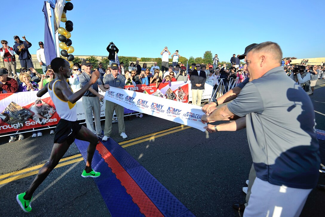 Retired Army Gen. Gordon R. Sullivan, president and chief operating officer of the Association of the United States Army, Army Chief of Staff Gen. Raymond T. Odierno, Army Secretary John McHugh, and Sergeant Major of the Army Raymond F. Chandler III  hold a banner at the finish line for the winner of the 2011 Army Ten-Miler in Washington, D.C., Oct. 9, 2011.