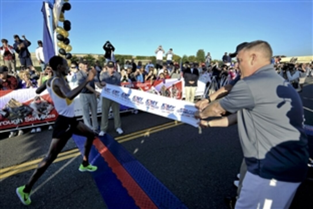 Retired Army Gen. Gordon R. Sullivan, president and chief operating officer of the Association of the United States Army; Army Chief of Staff Gen. Raymond T. Odierno; Army Secretary John McHugh; and Sergeant Major of the Army Raymond F. Chandler III hold a banner at the finish line for the winner of the 2011 Army Ten-Miler in Washington, D.C., Oct. 9, 2011. 