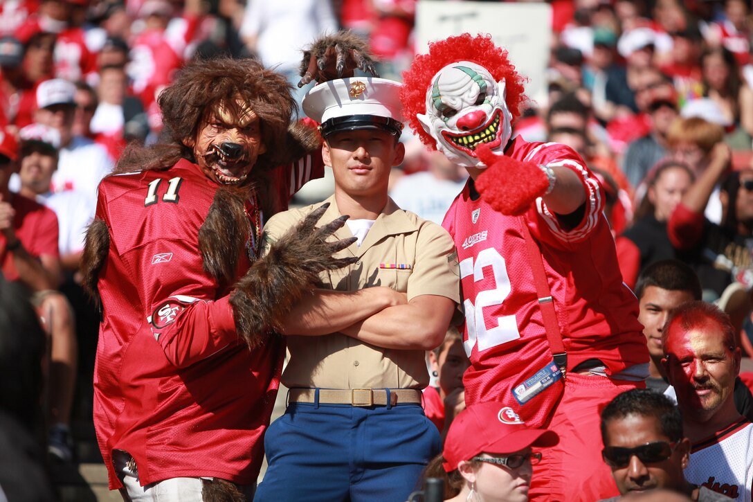 Lance Cpl. Timothy Lenzo, a combat correspondent with 1st Marine Division, poses with costumed San Francisco 49er fans during the 49ers Salute to Fleet Week football game, Oct. 9. During the game fans continuously approached service members to thank them for their service and take photos with them.