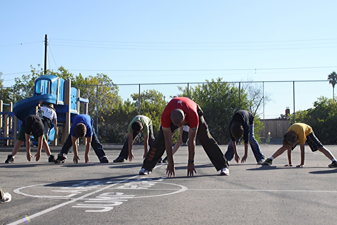 Staff Sgt. Jarvis Rodriguez, a drill instructor with 1st Recruit Training Battalion, Alpha Company, stretches with students during a visit to Holmes Elementary School as part of the Partnership in Education Program Tuesday. The PIE program consists of Marine volunteers visiting the school every other Tuesday to participate in physical educations classes in an effort to provide the students with positive role models.