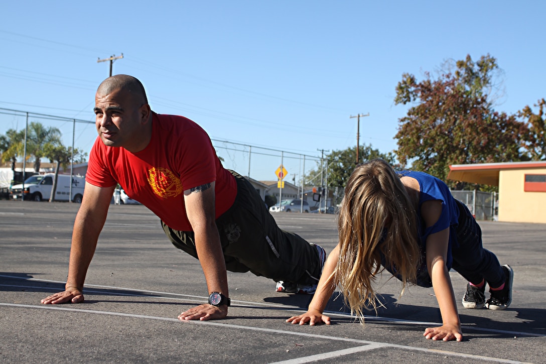 Staff Sgt. Jarvis Rodriguez, a drill instructor with 1st Recruit Training Battalion, Alpha Company, does pushups with a student during a visit to Holmes Elementary School as part of the Partnership in Education Program Tuesday. The PIE program consists of Marine volunteers visiting the school every other Tuesday to participate in physical educations classes in an effort to provide the students with positive role models.