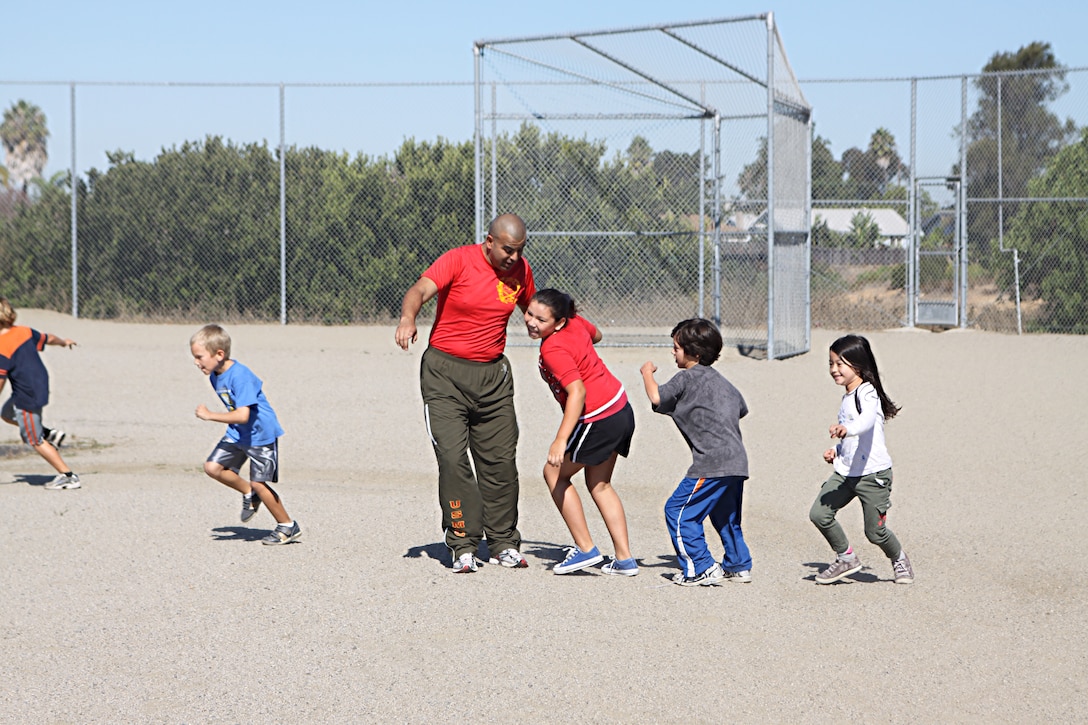 Staff Sgt. Jarvis Rodriguez, a drill instructor with 1st Recruit Training Battalion, Alpha Company, encourages students to run faster during a visit to Holmes Elementary School as part of the Partnership in Education Program Tuesday. The PIE program consists of Marine volunteers visiting the school every other Tuesday to participate in physical educations classes in an effort to provide the students with positive role models.