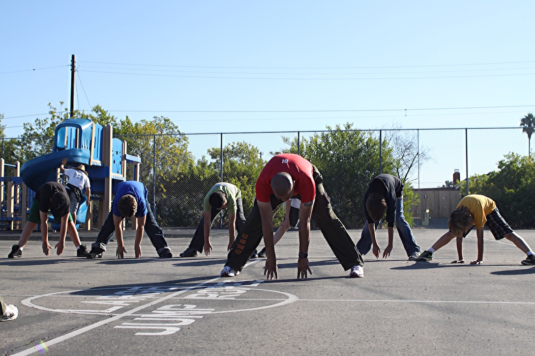 Staff Sgt. Jarvis Rodriguez, a drill instructor with 1st Recruit Training Battalion, Alpha Company, stretches with students during a visit to Holmes Elementary School as part of the Partnership in Education Program Tuesday. The PIE program consists of Marine volunteers visiting the school every other Tuesday to participate in physical educations classes in an effort to provide the students with positive role models.