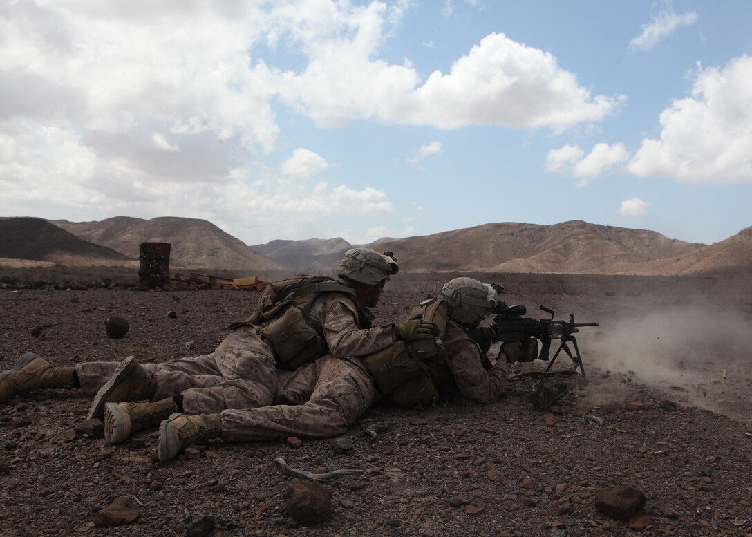 Lance Cpl. Calvin Jensen, left, a team leader with Echo Company, Battalion Landing Team, 2nd Battalion, 2nd Marine Regiment, 22nd Marine Expeditionary Unit (MEU), watches as Lance Cpl. Ryan T. Dupere, a squad automatic weapon (SAW) gunner with Echo Company, and Springville, N.Y., native, fires an M-249 SAW during a platoon-attack exercise ashore near Camp Lemonnier, Djibouti, October 11. Platoon-attack training was one of the many exercises conducted during the Marines’ six-day training evolution in Djibouti, Africa. The 22nd MEU is currently deployed as part of the Bataan Amphibious Ready Group (BATARG) as the U.S. Central Command theatre reserve force, also providing support for maritime security operations and theater security cooperation efforts in the U.S. 5th Fleet area of responsibility.