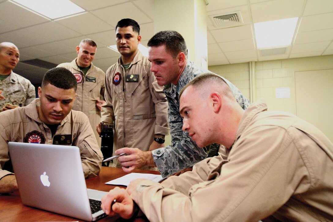 Marines and an airman from Aircraft Rescue and Firefighting formulate a detailed plan of attack for a fire scenario during the Fire Officer One course on Marine Corps Air Station Futenma Oct. 12.