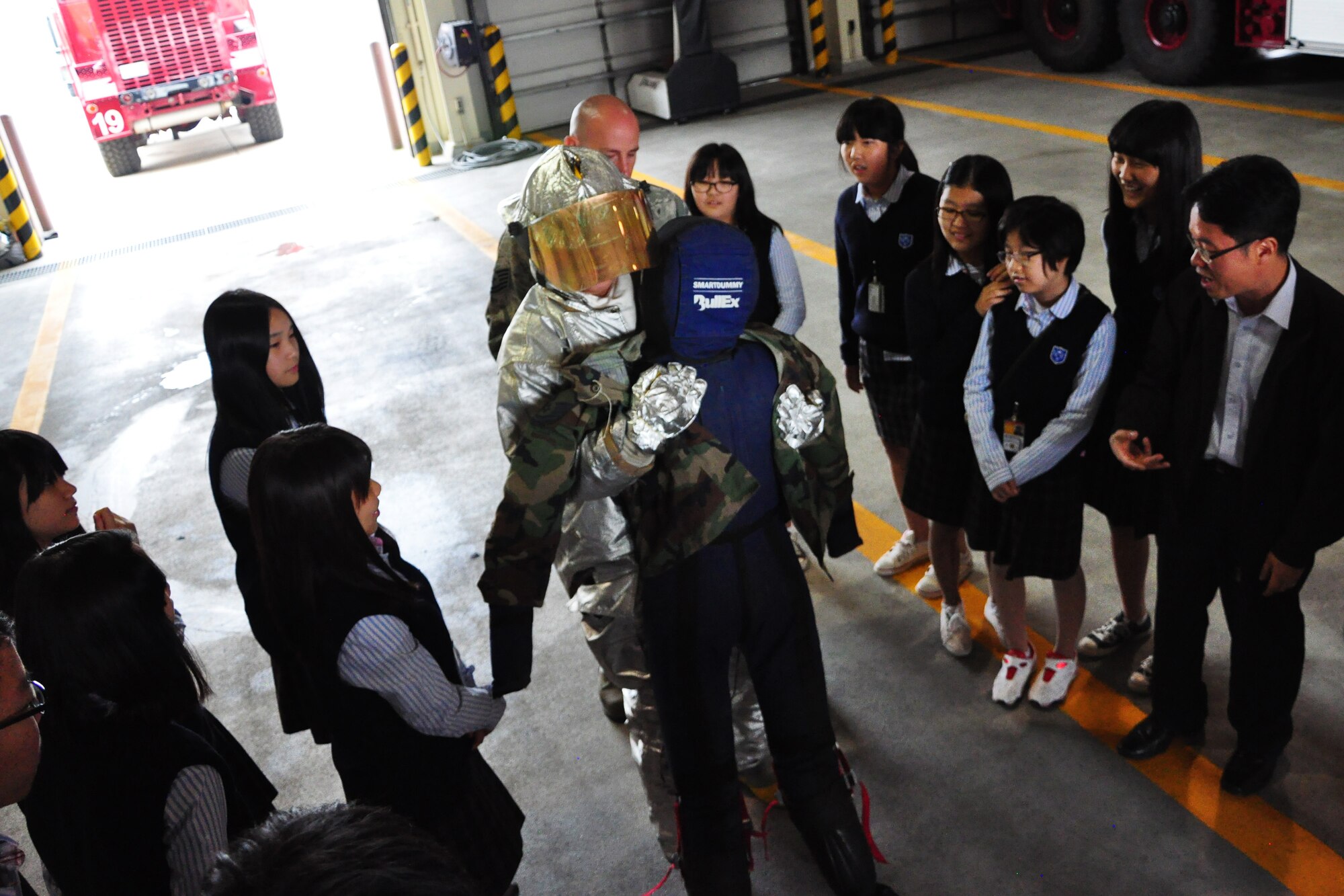 A student, dressed in firefighter gear, picks up a 50-pound dummy system during a visit to the Osan Fire Department Oct. 12, 2011. As a part of Fire Prevention Week, 21 students from a local Korean middle school toured the Osan Fire Department and got to see firsthand how a firefighter lives day to day. The students got to see several tools of the trade, learned about what a firefighter’s day is like and got a fire truck and ladder truck demonstration. Fire Prevention Week is the longest running public health and safety observance on record. (U.S. Air Force photo/Tech. Sgt. Chad Thompson)