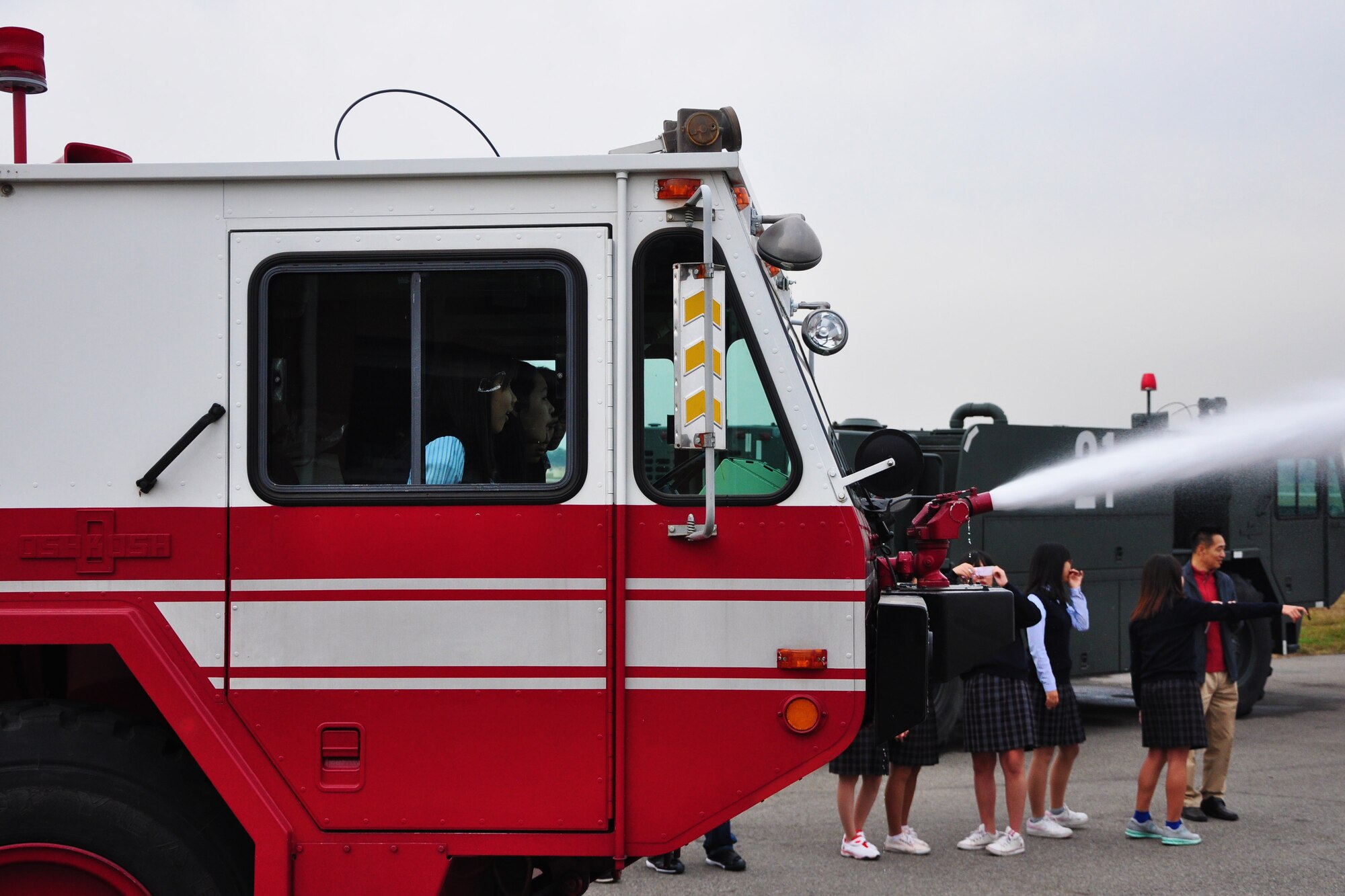 Students watch as a fire truck sprays water toward the flightline during a visit to the Osan Fire Department Oct. 12, 2011. As a part of Fire Prevention Week, 21 students from a local Korean middle school toured the Osan Fire Department and got to see firsthand how a firefighter lives day to day. The students got to see several tools of the trade, learned about what a firefighter’s day is like and got a fire truck and ladder truck demonstration. Fire Prevention Week is the longest running public health and safety observance on record. (U.S. Air Force photo/Tech. Sgt. Chad Thompson)