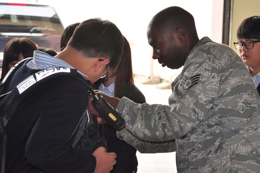 Staff Sgt. Casaree Whitaker, 51st Civil Engineer Squadron firefighter, helps a student put on a self-contained breathing apparatus during a visit to the Osan Fire Department Oct. 12, 2011. As a part of Fire Prevention Week, 21 students from a local Korean middle school toured the Osan Fire Department and got to see firsthand how a firefighter lives day to day. The students got to see several tools of the trade, learned about what a firefighter’s day is like and got a fire truck and ladder truck demonstration. Fire Prevention Week is the longest running public health and safety observance on record. (U.S. Air Force photo/Tech. Sgt. Chad Thompson)