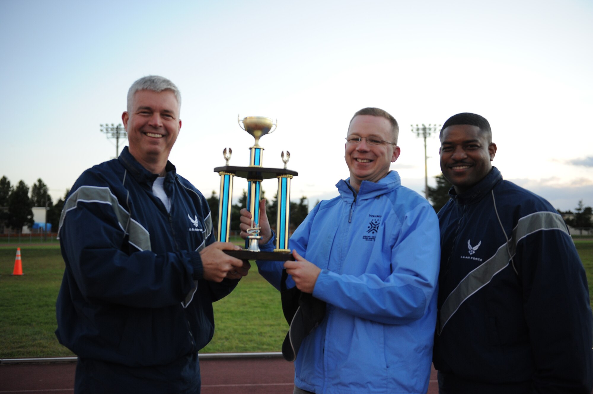 MISAWA AIR BASE, Japan -- Col. Van Wimmer, left, 35th Fighter Wing vice commander, and Chief Master Sgt. Phillip Easton, right, 35th Aircraft Maintenance Squadron, present Master Sgt. Charles Sutherland, 373rd Intelligence Surveillance Reconnaissance Group, with the trophy for the small squadron winner at the wing sports day here Oct. 7. Master Sgt. Charles Sutherland accepted the trophy on behalf of the Misawa Security Operations Center. The 35th Fighter Wing held a sports day to promote physical fitness, teamwork, competition, sportsmanship and esprit de corps. The day was kicked off with a 3-mile run followed by various sporting events to include relay races, basketball, softball, ultimate frisbee, soccer and a readiness competition. Approximately 14 units from the base formed teams to participate in each event. (U.S. Air Force photo/Airman 1st Class Kia Atkins)