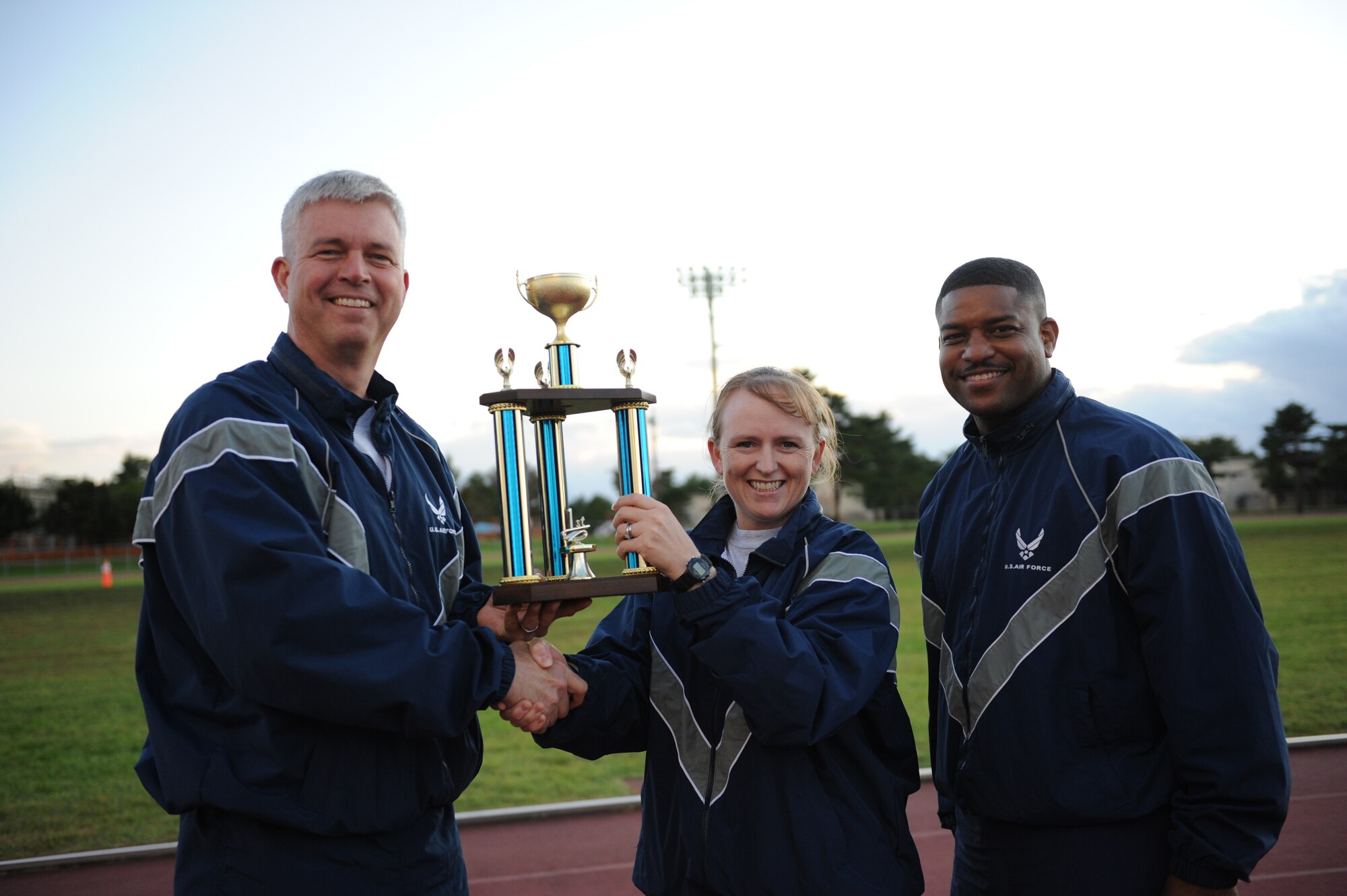 MISAWA AIR BASE, Japan -- Col. Van Wimmer, left, 35th Fighter Wing vice commander, and Chief Master Sgt. Phillip Easton, right, 35th Aircraft Maintenance Squadron, present Lt. Col. Kelly Jost, 35th Maintenance Squadron commander, with the big squadron winner trophy for wing sports day here Oct. 7. The 35th Fighter Wing held a sports day to promote physical fitness, teamwork, competition, sportsmanship and esprit de corps. The day was kicked off with a 3-mile run followed by various sporting events to include relay races, basketball, softball, ultimate frisbee, soccer and a readiness competition. Approximately 14 units from the base formed teams to participate in each event. (U.S. Air Force photo/Airman 1st Class Kia Atkins)