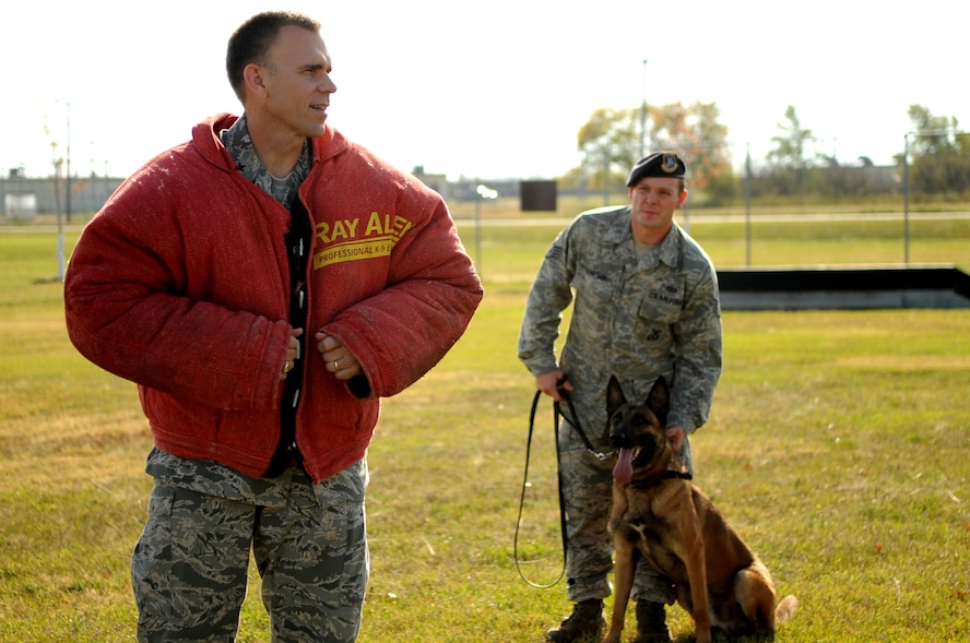 Brig. Gen. Timothy Green, Director of Installations and Mission Support for the U.S. Air Force Air Mobility Command, waits for the call to run while Staff Sgt. Rocky Thompson, 319th Security Forces Squadron K-9 handler, gives Zumba the signal to attack during a demonstration at Grand Forks Air Force Base, N.D., on Oct. 12. General Green was at Grand Forks for a site visit and to participate in the U.S. Air Force Expeditionary Center Commander’s Conference. (U.S. Air Force photo by Senior Airman Amanda N. Stencil)