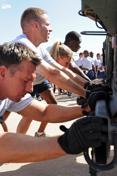Dyess airmen push an armored HUMVEE as a part of the Wingman Olympics, Oct. 7, 2011, at Dyess Air Force Base, Texas. The flight line was used for many activities to include a HUMVEE push, tug-o-war and static displays. (U.S. Air Force photo by Airman 1st Class Peter Thompson/Released)