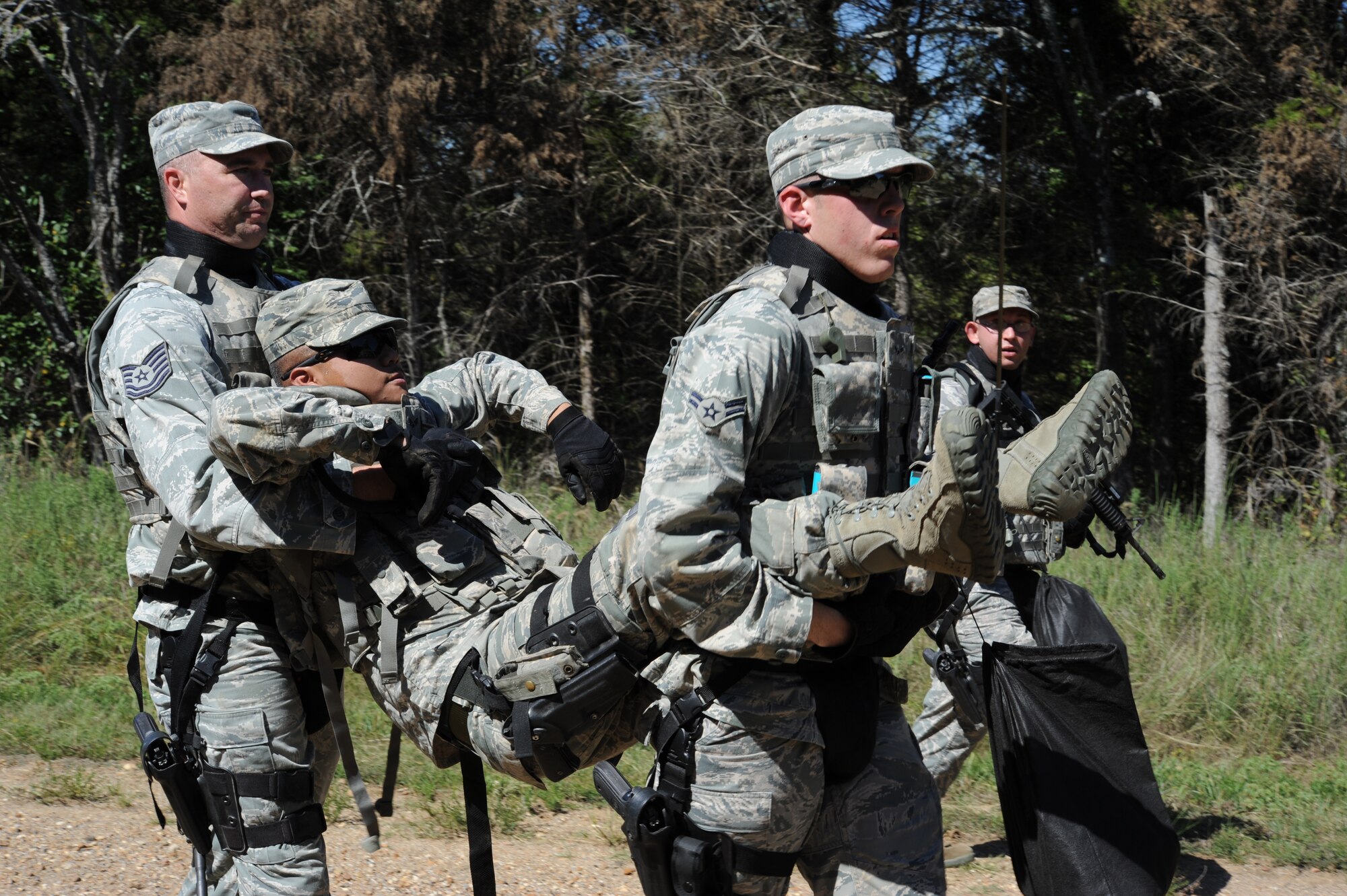 Tech. Sgt. Scott Robertson and Airman 1st Class Bradley Browning, 71st Security Force Squadron members at Vance Air Force Base, Okla., carry Senior Airman Brian Sebastian, a simulated causality, during a field training exercise at Camp Gruber, Okla., Sept. 27. During the day-long training, the Airmen fired at pop-up targets and executed a weapons-cache search and seizure scenario using simunitions. (U.S. Air Force photo/ Staff Sgt. James Bolinger)