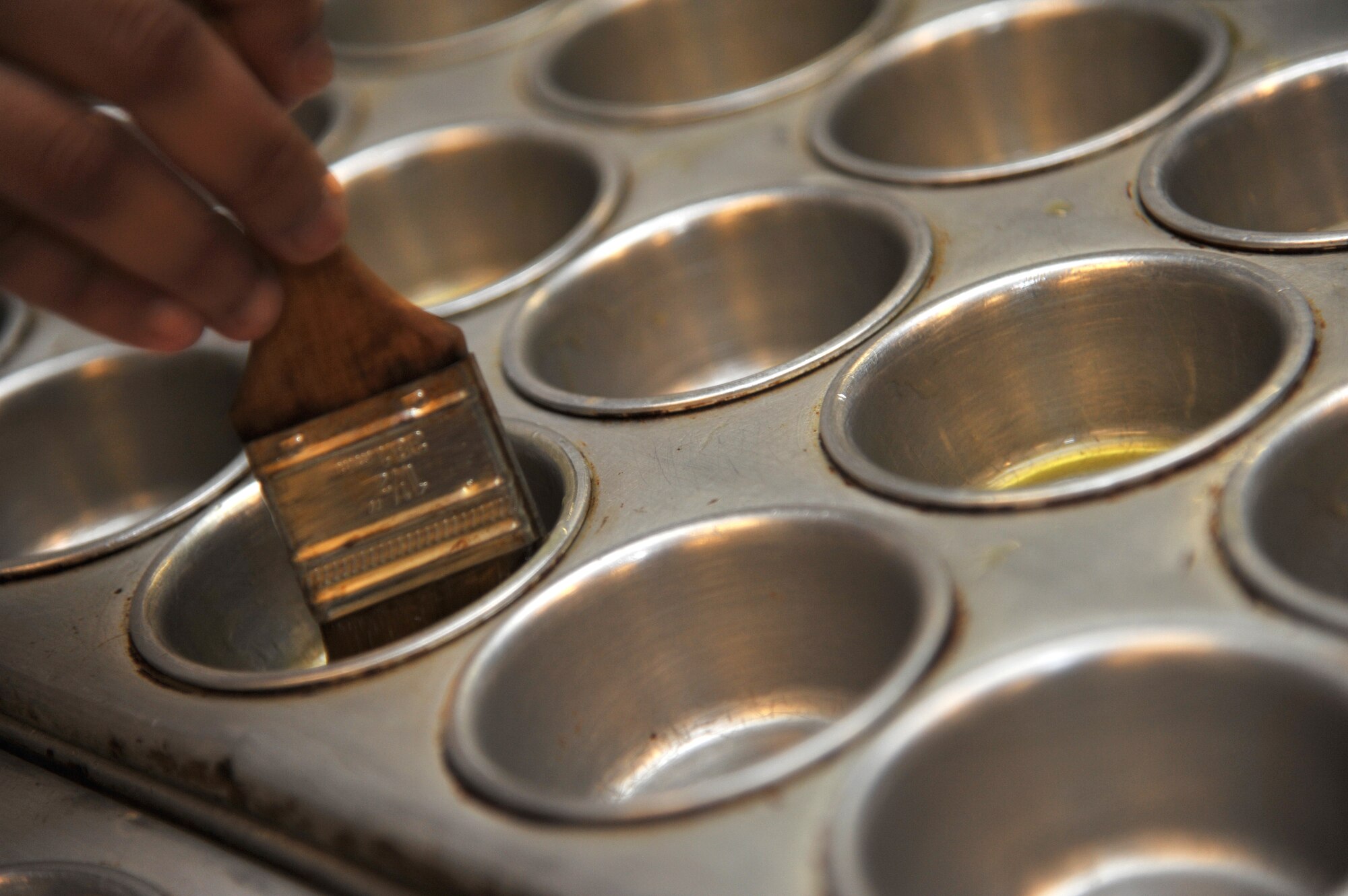Senior Airman Gretchen Sarmiento, 633rd Force Support Squadron cook, prepares baking pans for muffin batter at the Crossbow Dining Facility at Langley Air Force Base, Va., Oct. 6, 2011.  Langley AFB is one of the finalists contending with Beale AFB, Calif., for the 2012 Air Combat Command John L. Hennessy Trophy. (U.S. Air Force photo by Airman 1st Camilla Griffin/Released)