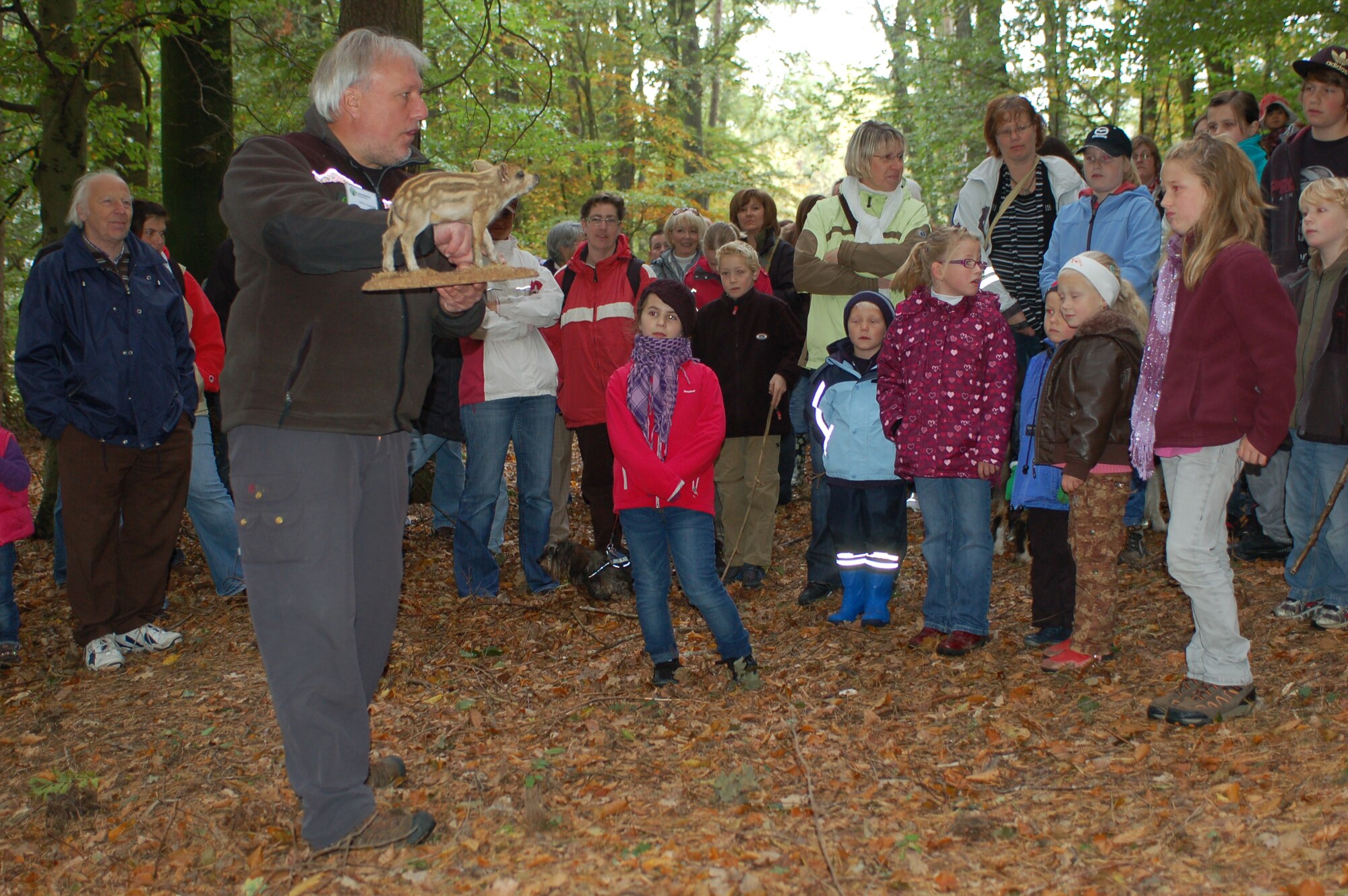 BINSFELD, Germany -- A local forest master explains how a wild boar finds and tracks acorns during the annual forest walk here Oct. 9. He held a stuffed boar in his hands and explained that the boar doesn’t see very well but finds acorns by smell. The children found acorns and treats on the forest ground themselves after the forest master asked them to wear eye covers and experience nature without their sight. Nearly 100 people came to the walk that went through the Binsfeld Kaasweg forested area. The forest master taught children about trees, plants and animals in the Eifel area during the walk. The community invited all participants to a traditional soup luncheon at the town hall after the walk. (U.S. Air Force photo/Iris Reiff)