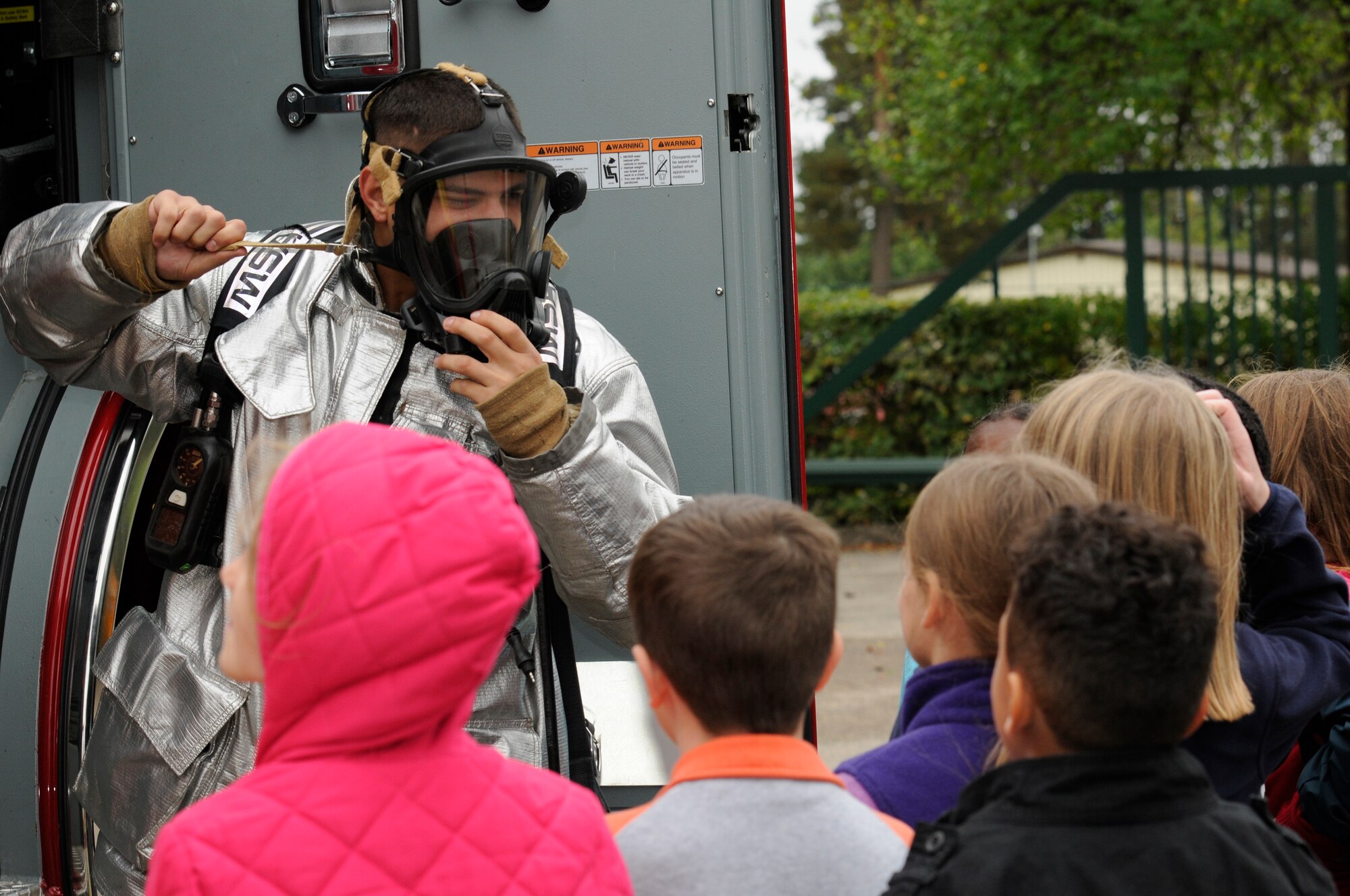 SPANGDAHLEM AIR BASE, Germany -- Airman 1st Class Spencer Quinn, 52nd Civil Engineer Squadron firefighter, shows a gas mask to children from the Spangdahlem Elementary School during a fire safety demonstration here Oct. 12. National Fire Prevention Week is a week-long schedule of events that promotes fire safety and prevention through demos, visits from Sparky the Fire Dog and a parade in Spangdahlem housing. (U.S. Air Force photo/Airman 1st Class Brittney Frees)