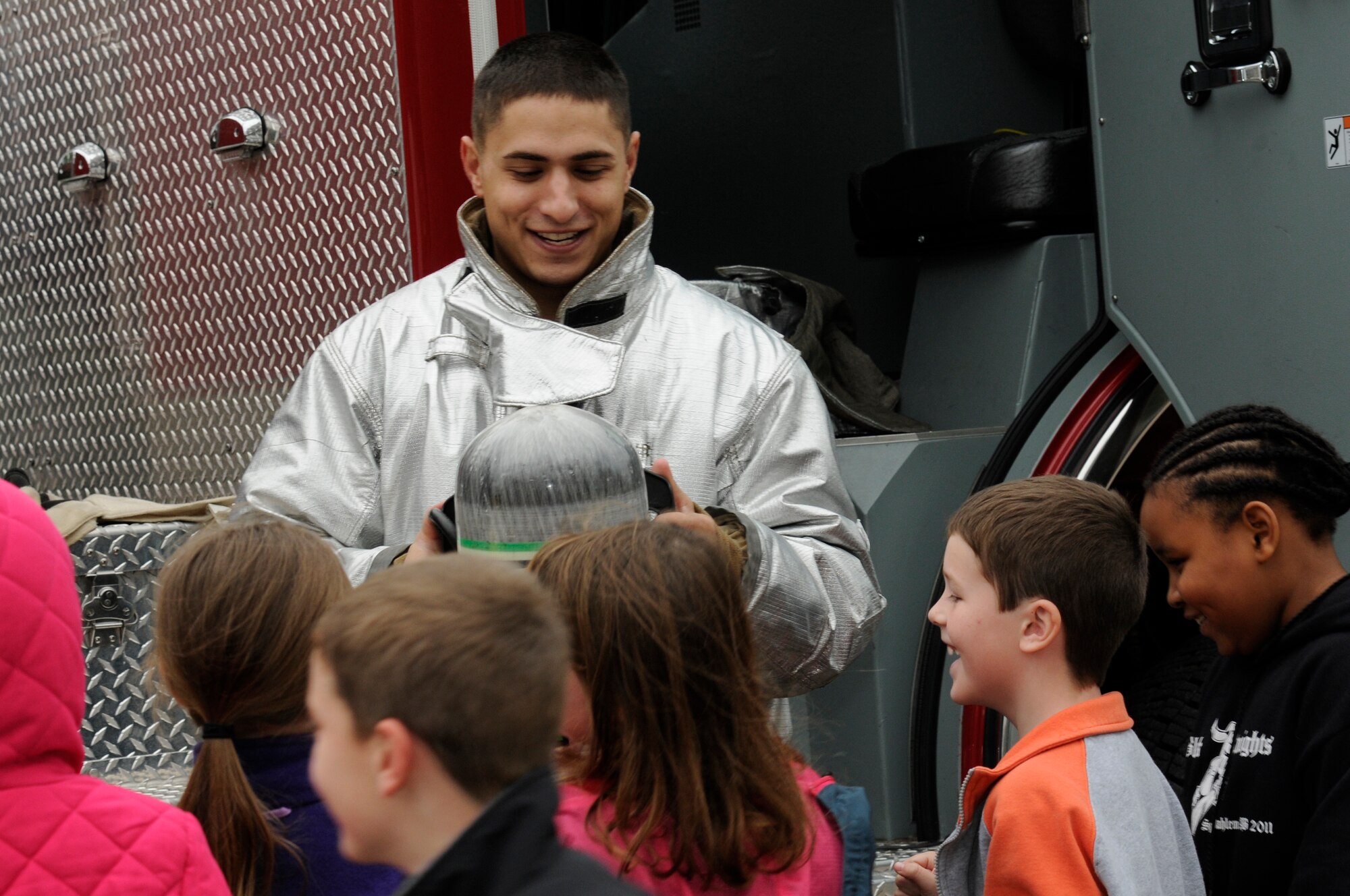 SPANGDAHLEM AIR BASE, Germany -- Airman 1st Class Spencer Quinn, 52nd Civil Engineer Squadron firefighter, shows an oxygen tank to children from the Spangdahlem Elementary School during a fire safety demonstration here Oct. 12. National Fire Prevention Week is a week-long schedule of events that promotes fire safety and prevention through demos, visits from Sparky the Fire Dog and a parade in Spangdahlem housing. (U.S. Air Force photo/Airman 1st Class Brittney Frees)