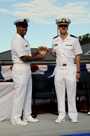Ensign Andrew Riegert receives the Vice Adm. Behrens award plaque from keynote speaker Master Chief Petty Officer Gamal Coles, during the Naval Nuclear Power Taining Command graduation ceremony for class 1104 at Joint Base Charleston - Weapons Station, Oct. 7. The plaque is awarded to the graduating officer with the highest grade-point average. Riegert earned an overall GPA of 3.77. Gamal is the NNPTC command master chief. (U.S. Navy photo/Petty Officer 3rd Class Brannon Deugan)