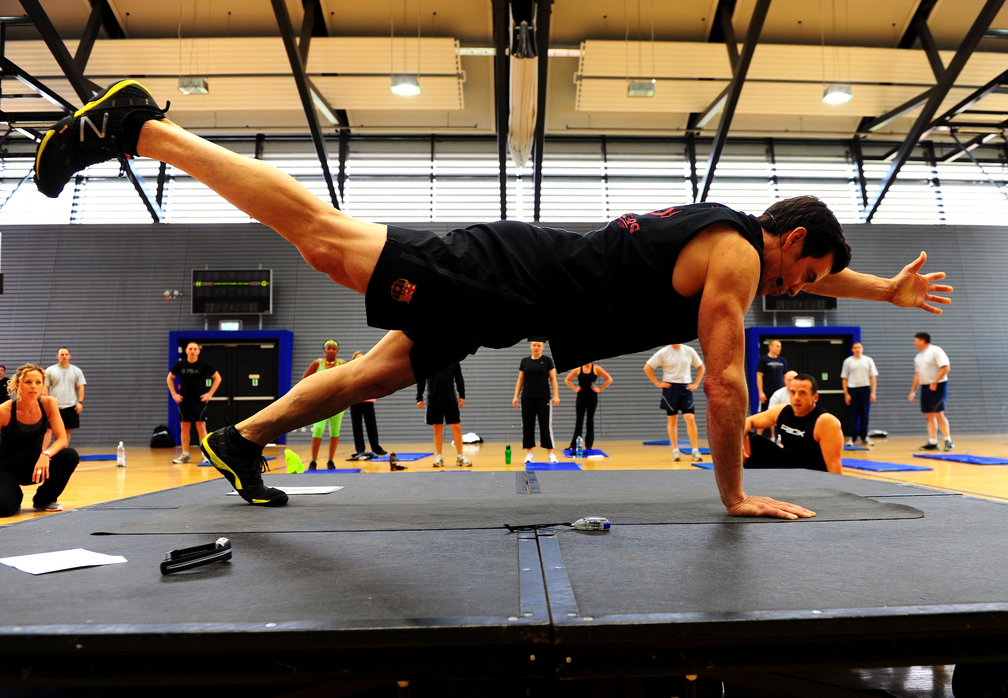 Tony Horton, creator of workout program P90X, demontrates an excercise during a calisthenics routine at the southside gym, Ramstein Air Base, Germany, Oct. 7, 2011. Horton conducted two free strength training workout sessions for 325 military personnel and dependents. (U.S. Air Force photo by Airman 1st Class Brea Miller)