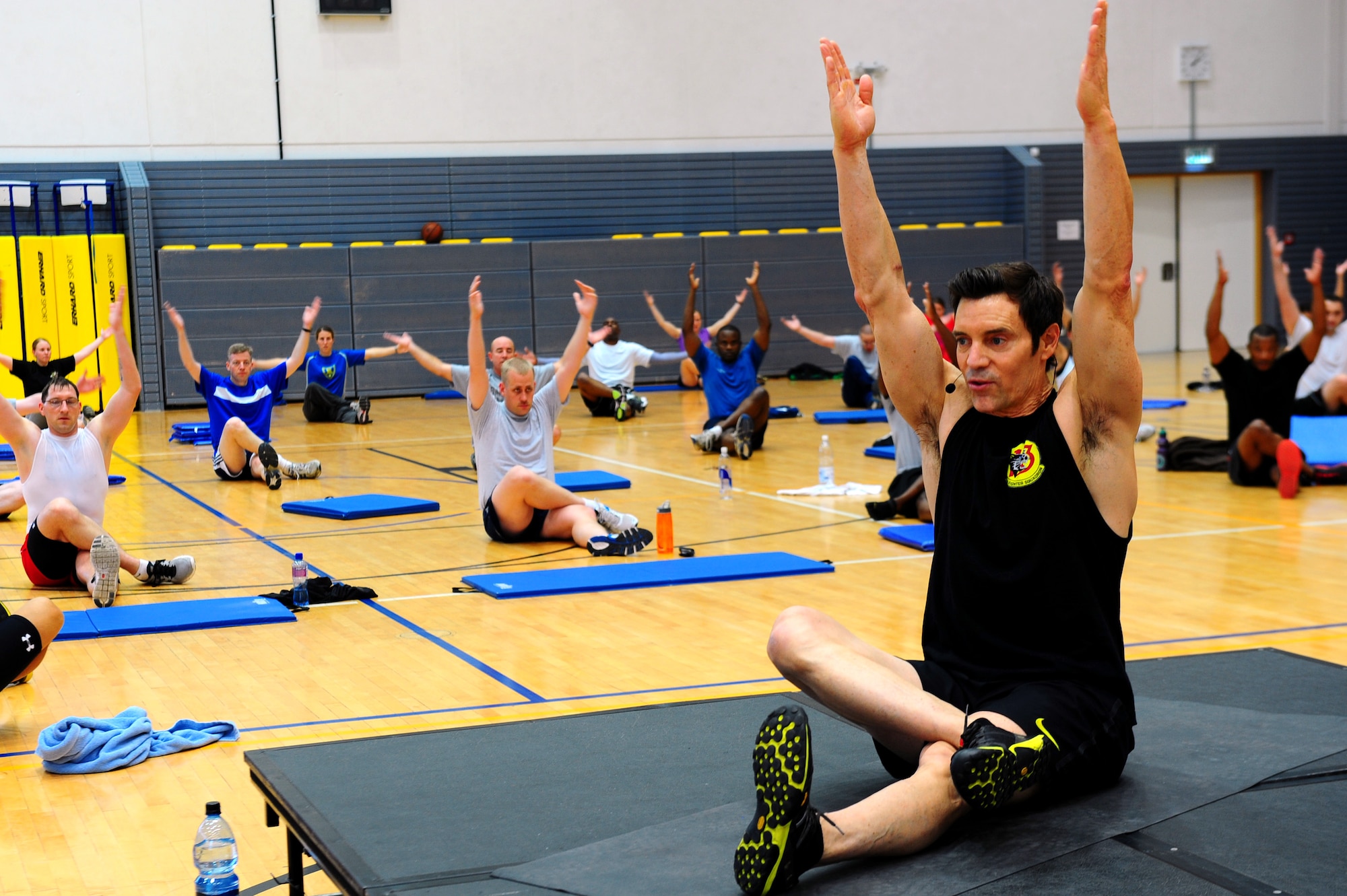 Tony Horton, creator of workout program P90X, leads a warm-up stretch before a calisthenics routine at the southside gym, Ramstein Air Base, Germany, Oct. 7, 2011. Horton conducted two free strength training workout sessions for 325 military personnel and dependents. (U.S. Air Force photo by Airman 1st Class Brea Miller)