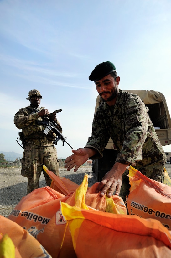 An Afghan soldier sets down a bag of rice after it is weighed as U.S ...