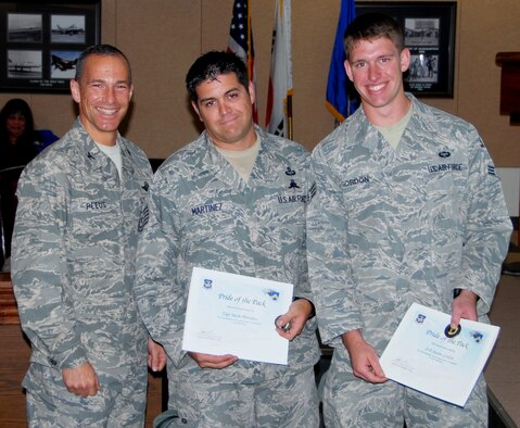 Col. Scott L. Pleus, 8th Fighter Wing commander, presents the Pride of the Pack award to Tech. Sgt. Jason Martinez and Senior Airman Justin Gordon, both 8th Operations Support Squadron Survival, evasion, resistance and escape specialists, at Kunsan Air Base, Republic of Korea, Oct. 14. (U.S. Air Force photo by Capt. Omar Villarreal/Released)
