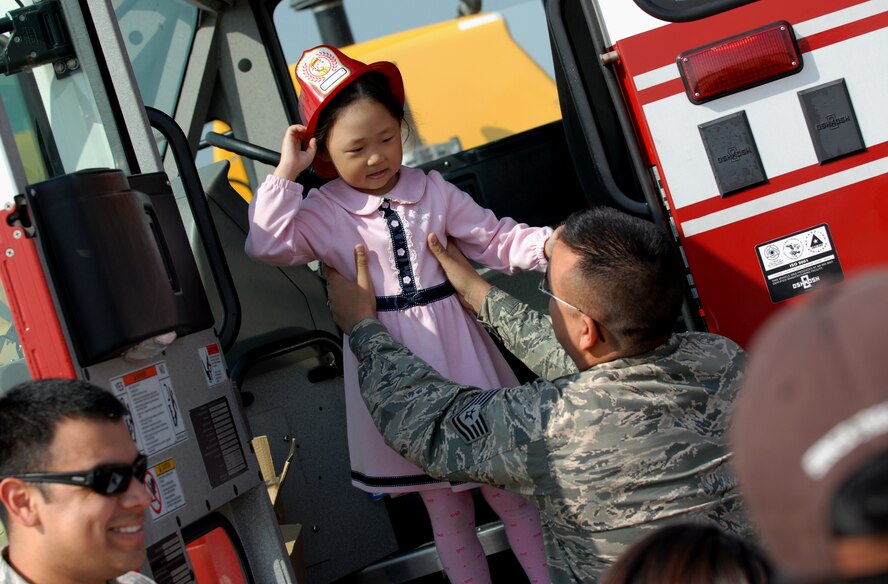 A young Korean girl is helped out of a fire truck by Tech. Sgt. Alex Retamoza, 8th Civil Engineer Squadron firefighter, following her familiarization of the “shiny red truck” during the 2011 Gunsan-Saemangeum Air Show at Kunsan Air Base, Republic of Korea, Oct. 8, 2011. The air show featured many static displays and performances from across the Pacific Air Forces and Korean peninsula. (U.S. Air Force photo by Senior Airman Benjamin Stratton/Released)