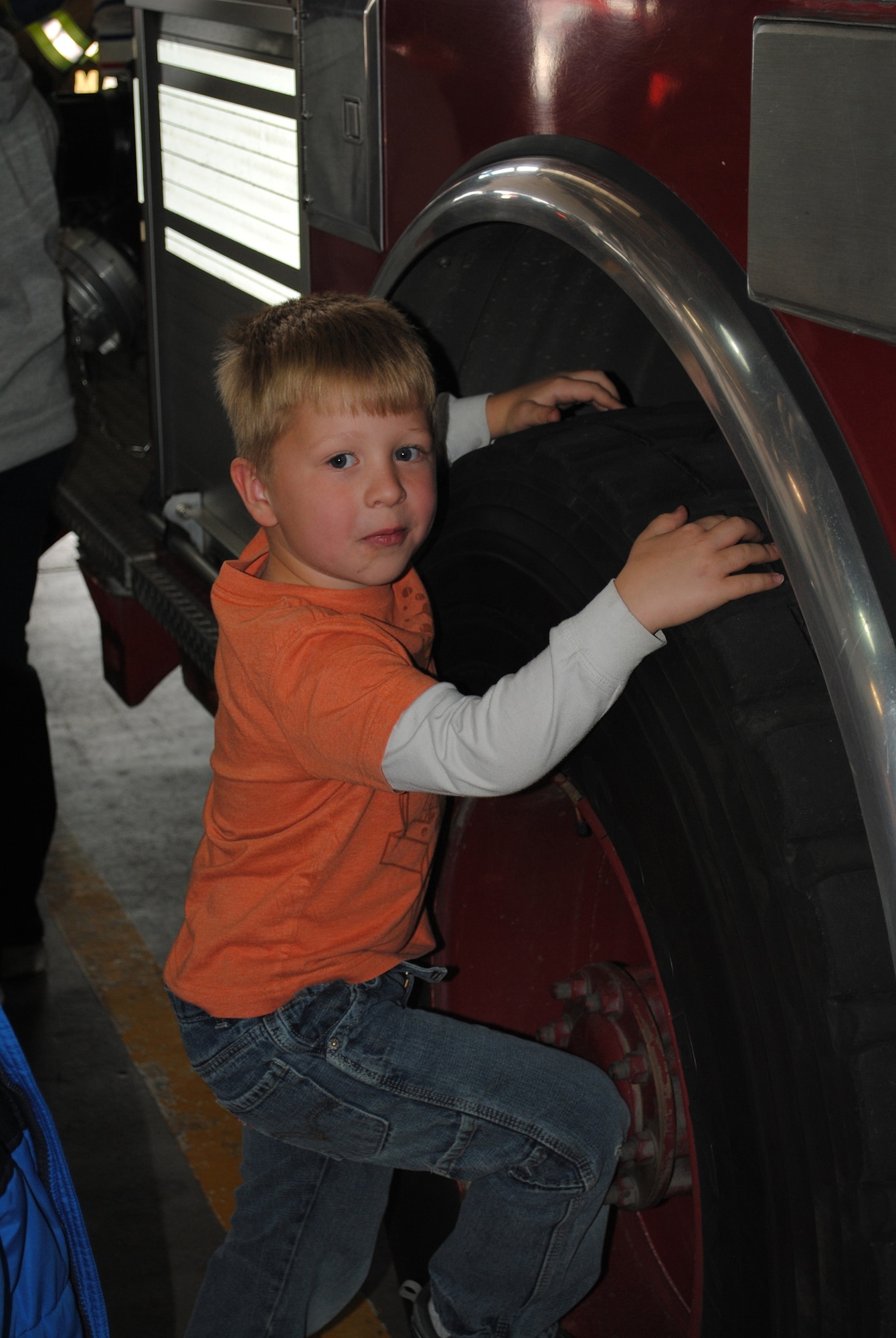 Gunner Webb, 5, attempts climbing up on the wheel of a fire truck while waiting his turn to explore the inside of it.  (U.S. Air Force photo/Airman Cortney Paxton)