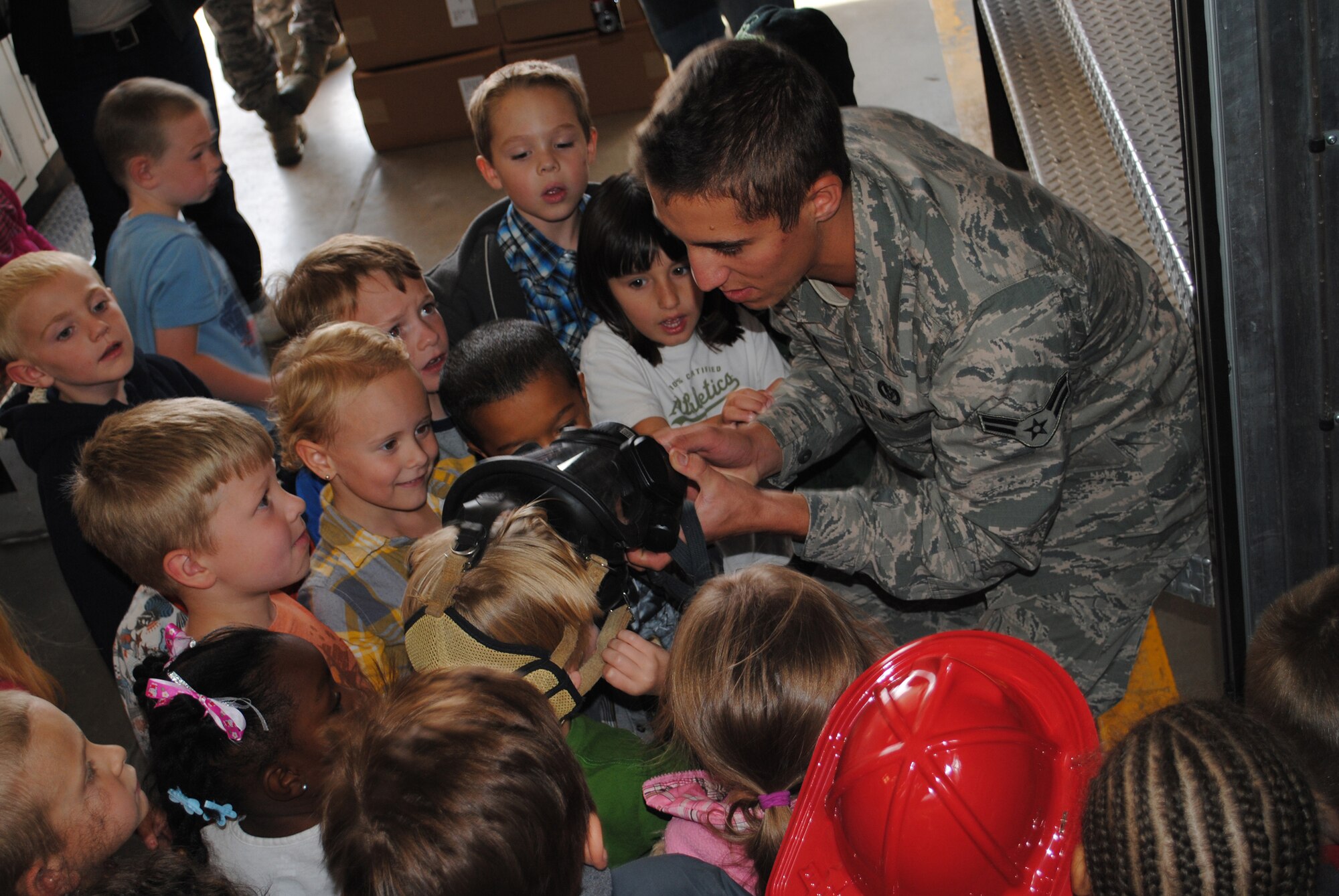 Airman 1st Class Cody Ripka, 341st Civil Engineer Squadron fire fighter, helps a student try on some of the protective equipment during a tour of the Malmstrom Fire Station. Approximately 70 students and 15 teachers and parents participated in celebration of Fire Prevention Week.  (U.S. Air Force photo/Airman Cortney Paxton)