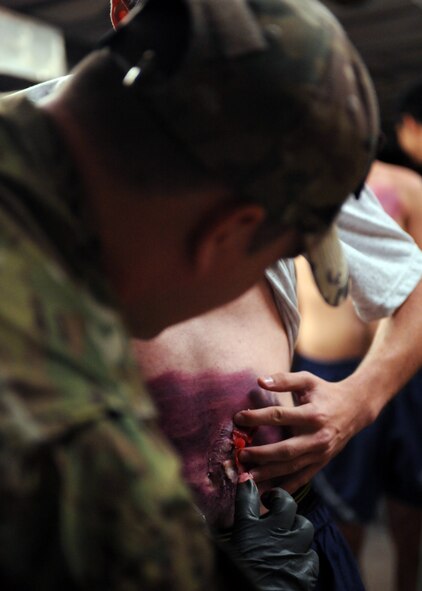 DAVIS-MONTHAN AIR FORCE BASE, Ariz. – Senior Airman Zachary Marker, 563rd Operations Support Squadron independent duty medical technician, applies makeup to the stomach of a volunteer at his moulage station during the Angel Thunder exercise here Oct. 11. Approximately 1,400 U.S. Military, federal and state employees, and coalition forces are participating in the fifth-annual Angel Thunder exercise, the largest military combat search and rescue exercise in the world. (U.S. Air Force photo/Airman 1st Class Timothy D. Moore)