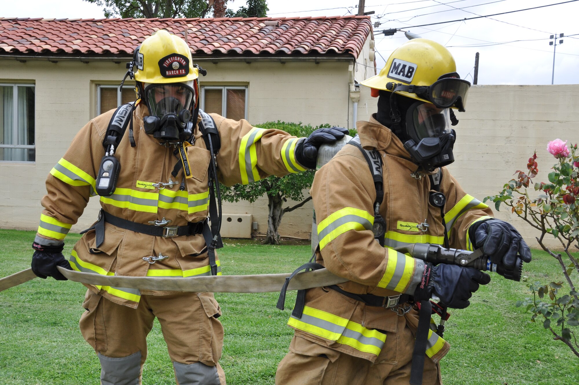 Fire fighters John Portugal and Johann Lusinger demonstrate how they would work as a team to fight a structural fire at one of the Gilley Houses off Graeber St., at March Air Reserve Base, Calif., Oct. 4, 2011. The March Fire Department observed Fire Prevention Week Oct. 11-14 this year.  (U.S. Air Force photo/Staff Sgt. Megan Crusher)