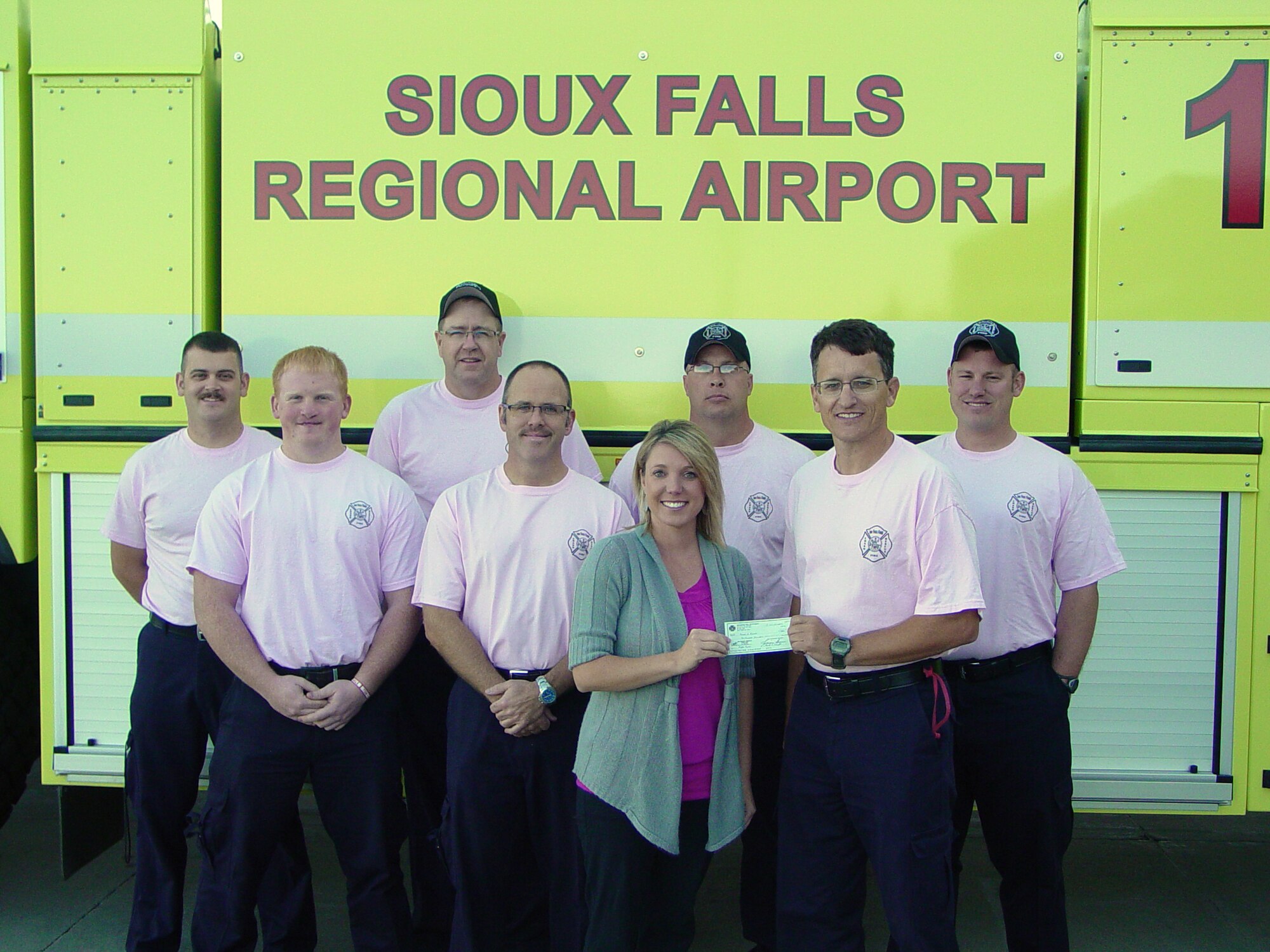 SIOUX FALLS, S.D. - Members of the B shift of the Crash, Fire, Rescue station at Joe Foss Field present a check for 600 dollars to Amanda Anderson, South Dakota Executive Director of the Susan G. Komen Foundation, on behalf of all the firefighters at the station October 13, 2011.  Firefighters at the station raised funds to support the foundation during the month of October which is Breast Cancer Awareness month as well as Fire Prevention month. (National Guard photo by Master Sgt. Thomas Krier)(RELEASED)