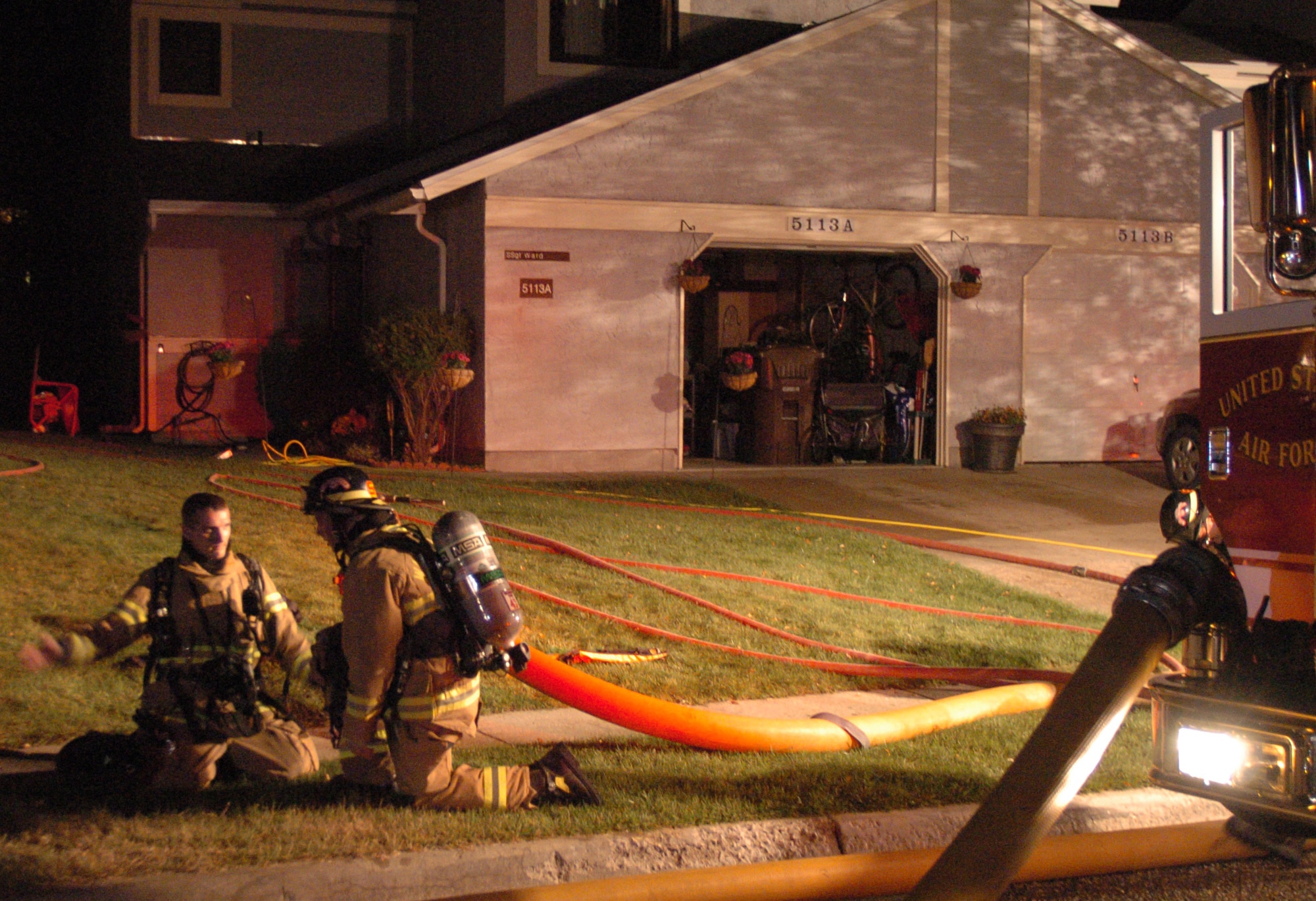 Senior Airman Jeffrey Rutledge and another firefighter with the 90th Civil Engineer Squadron take a rest after exiting the fire while at the scene of a house fire on Minuteman Drive Oct. 2. According to Gregory Chesser, 90th CES assistant fire chief, the preliminary damage estimate for the fire, which was caused by unattended cooking, is $25,000. (U.S. Air Force photo by R.J. Oriez)