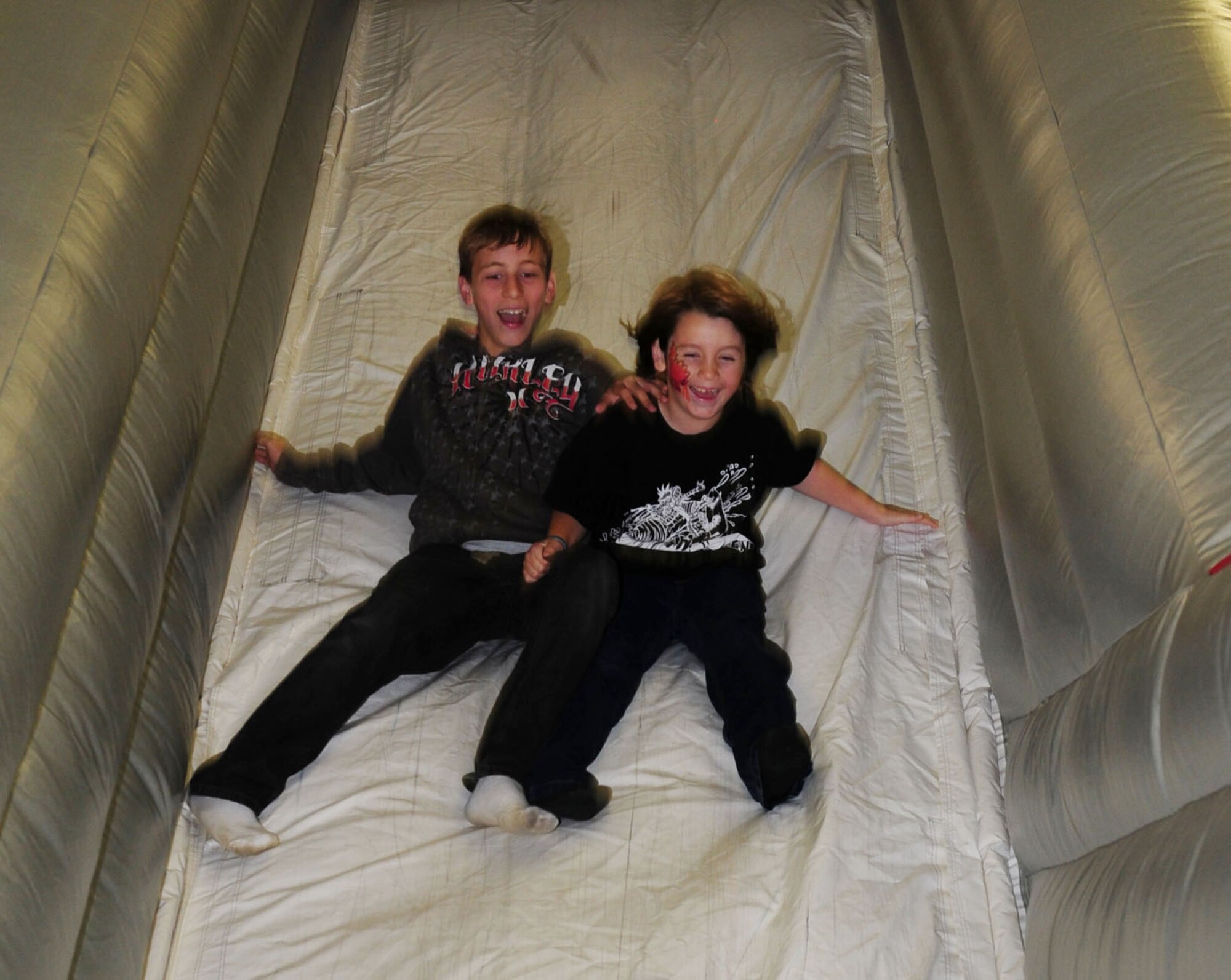 RAF MILDENHALL, England -- Joshua Oakley (left), 13, son of Staff Sgt. Matthew Milligan, 100th Maintenance Squadron, and Sarah Milligan; and Michael Mucha, 8, son of Staff Sgt. Michael Mucha, 48th Civil Engineer Squadron, and Amanda Mucha, speed down the fire truck bouncy slide at the RAF Mildenhall Fire Department open house Oct. 10, 2011. The open house was one of several events put on as part of Fire Prevention Week, and included various fire demonstrations, competitions for children and adults, a bouncy castle, crafts and a visit from Sparky the Fire Dog and Firefighter Gary. (U.S. Air Force photo by Karen Abeyasekere)