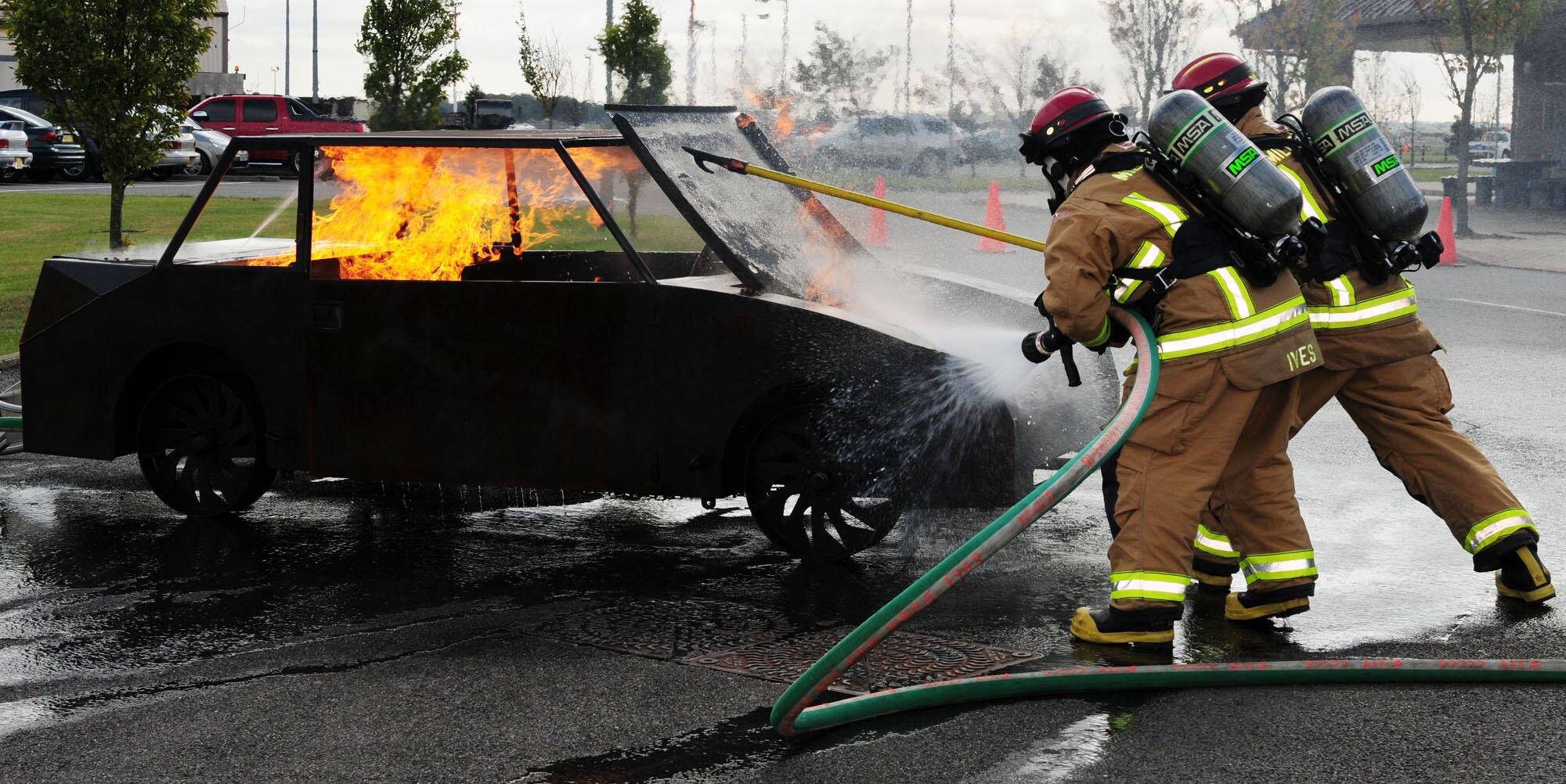 RAF MILDENHALL, England -- Crew Manager David Ives, left, and Staff Sgt. Gaspar Vela, 100th Civil Engineer Squadron Fire Department,extinguish a fire on a mock car during a demonstration at their open house here Oct. 10, 2011, as part of Fire Prevention Week. A Team Mildenhall fun run Oct. 14 will close out the week's events. (U.S. Air Force photo by Karen Abeyasekere)