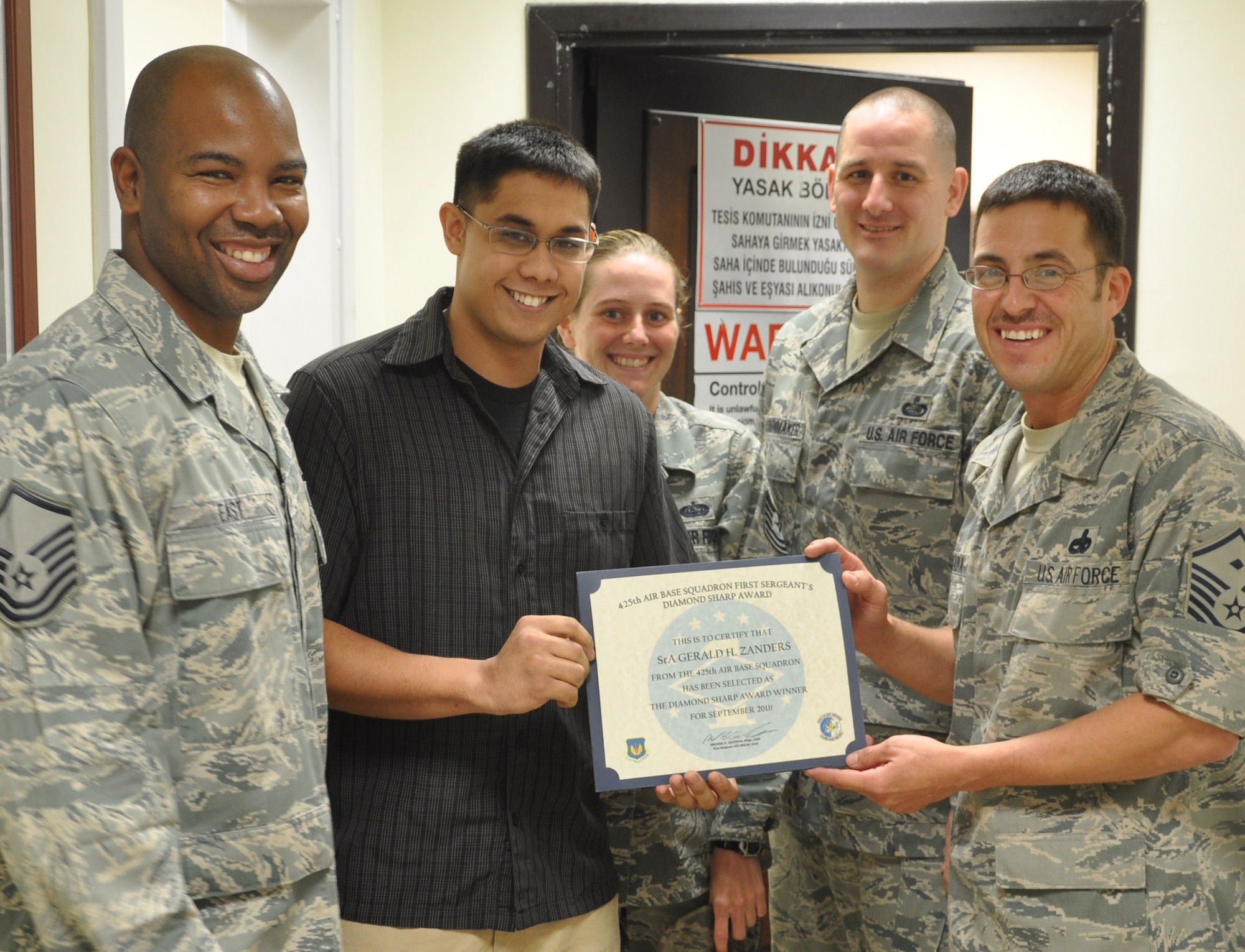 Senior Airman Gerald Zanders, 425th Air Base Squadron Airman, receives the Diamond Sharp Award from Master Sgt. Michael Quezada, 425th ABS first sergeant, right, and Master Sgt. Roderick East, 425th ABS superintendent, left, Oct. 13, 2011, at Izmir, Turkey. Senior enlisted leaders present the Diamond Sharp Award to Airmen with exceptional leadership and superior job performance. (U.S. Air Force photo by Tanju Varlikli/Released)