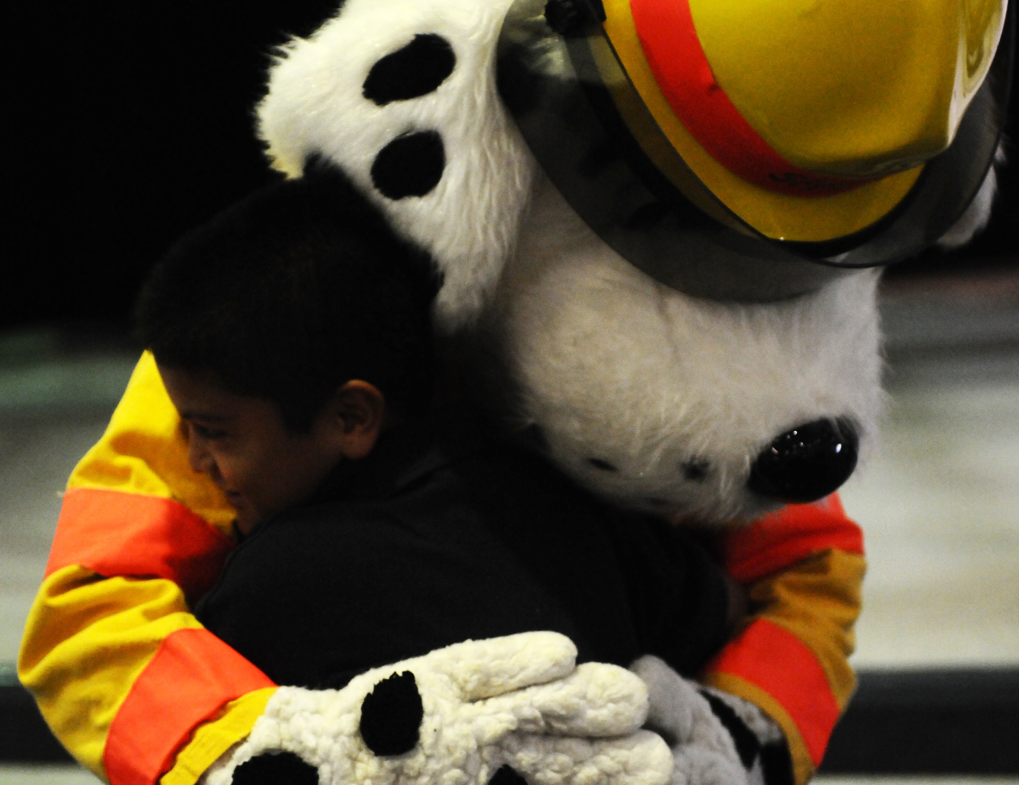 ANDERSEN AIR FORCE BASE, Guam—Sparky the Dog hugs a child from the Andersen Elementary School during a visit here, Oct. 13. The Andersen Fire and Emergency flight held nearly 30 classes to inform school children about fire prevention. (U.S. Air Force photo by Senior Airman Benjamin Wiseman/Released)