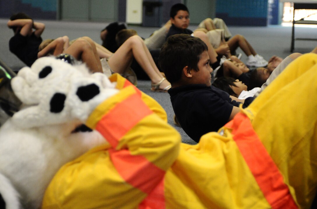 ANDERSEN AIR FORCE BASE, Guam—Sparky the Dog does sit-ups with fourth-grade children at Andersen Elementary School here, Oct. 13. Sparky and Andersen Fire department members visited the school to teach children about fire prevention during Fire Prevention Week. (U.S. Air Force photo by Senior Airman Benjamin Wiseman/Released)
