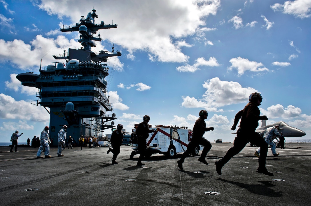 Flight deck personnel run to man hose teams and combat a simulated aircraft fire during a mass casualty drill on the flight deck aboard the aircraft carrier USS Carl Vinson in the Pacific Ocean, Oct. 6, 2011. The Carl Vinson Carrier Strike Group is under way conducting operations off the coast of Southern California.