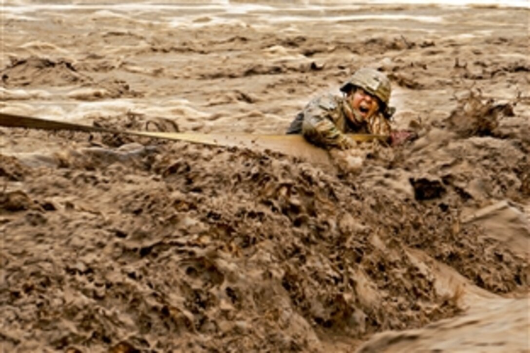U.S. Army Staff Sgt. Patrick Reynolds fights racing water while holding on to a tow strap attached to an Afghan army vehicle stuck in the Lurah River in Afghanistan's Shinkai district, Oct. 12, 2011. Reynolds is a squad leader assigned to Provincial Reconstruction Team Zabul.