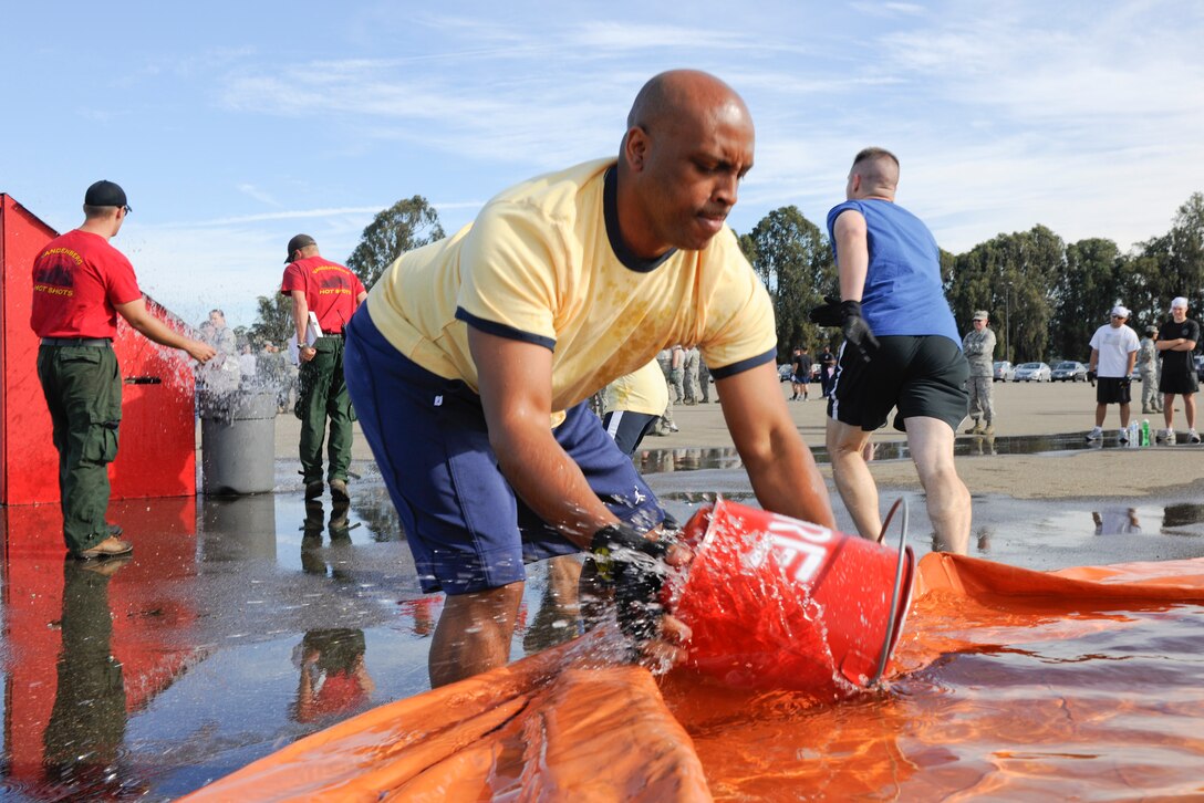 VANDENBERG AIR FORCE BASE, Calif. -- Senior Master Sgt. Rodney Bryant, 14th Air Force standardization and evaluation manager scoops water from a pool to assist his team with bucket brigade portion of the Fire Muster competition at the parade grounds here Friday, Oct. 14, 2011. The Fire Muster competition is held during Vandenberg’s Fire Prevention week to help demonstrate the physical and mental struggles that firefighters go through. (U.S. Air Force/Staff Sgt. Levi Riendeau)