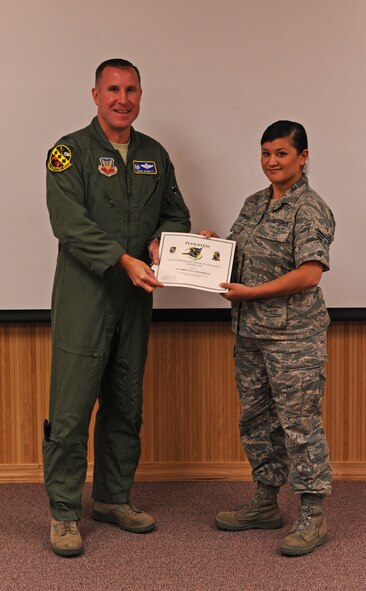 Col. Mark Bennett, 7th Operations Group commander, presents Senior Airman Brittany Jaramillo, 9th Bomb Squadron, with the Sept. Operations Group superior performer award, Oct. 13, 2011, at Dyess Air Force Base, Texas. Every month each group selects a person or team who has shown superior performance to be recognized in front of wing leadership. (U.S. Air Force photo by Airman 1st Class Peter Thompson/Released)